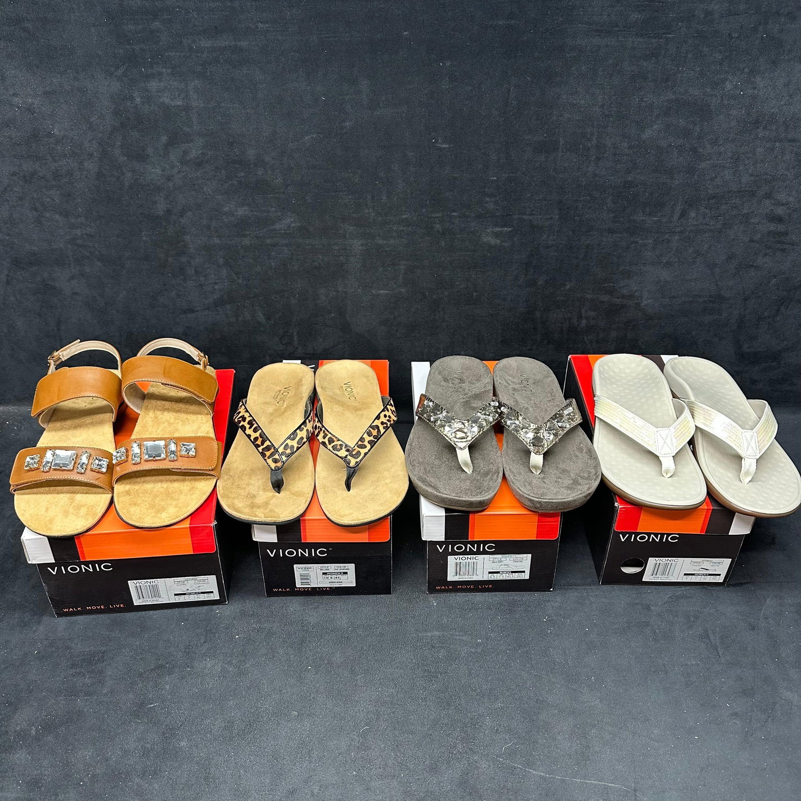 Vionic Women's Sandals Various Styles Four Pairs: Set of four pairs of Vionic womens sandals, including embellished leather straps, leopard print thongs, jeweled suede sandals, and iridescent white styles. Various sizes as shown on boxes, most