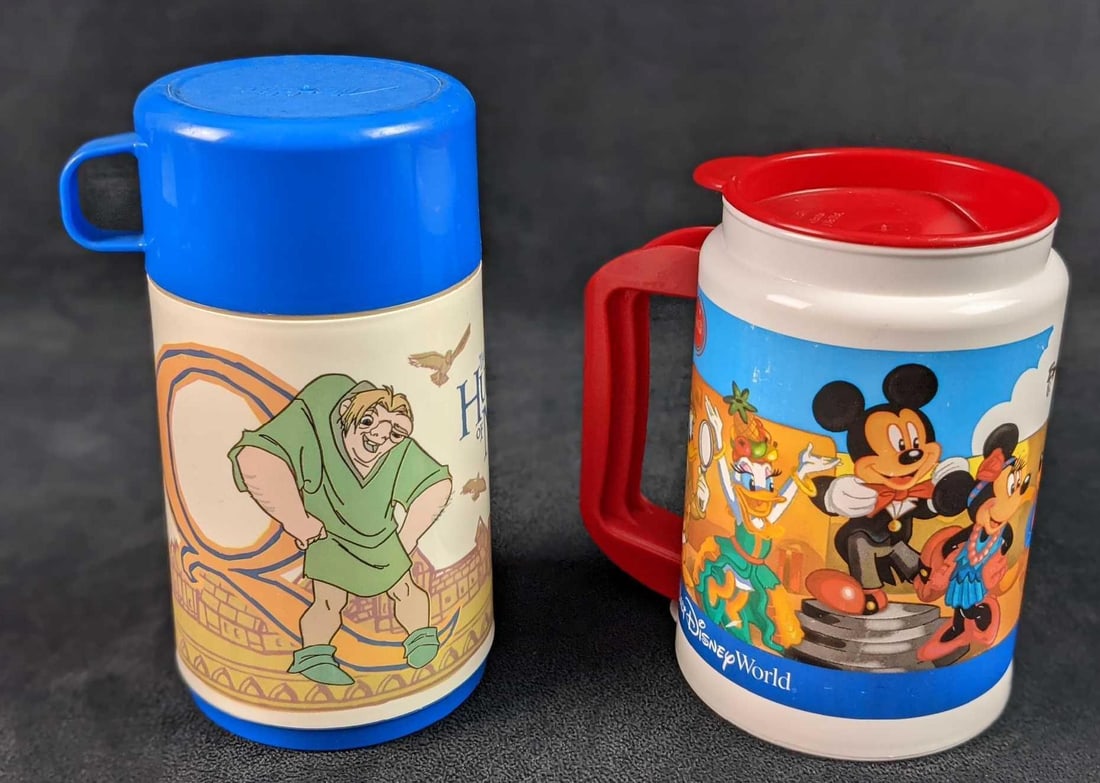 Disney Park Mug Hunchback Of Notre Dame Aladdin Thermos Style: This lot consists of: (1) Aladdin Hunchback Of Notre Dame Thermos. This is approx 4" x 3" x 6 1/2" (1) Disney Parks Plastic Mug With Handle And Top. Is approx 5 1/2" x 3 1/2" x 5 3