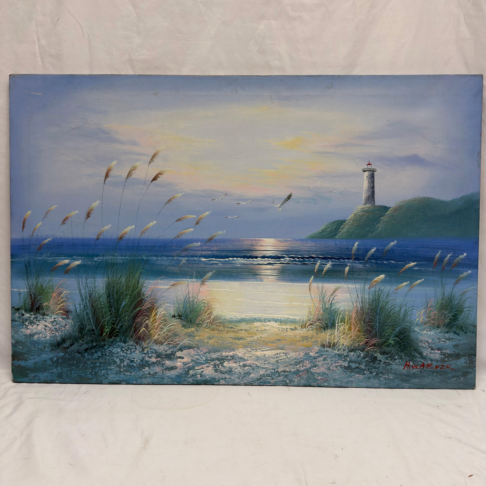 Signed Coastal Lighthouse Seascape Painting on Canvas: Original painting on canvas, signed in the lower right. This tranquil coastal scene depicts sea oats along a sandy shoreline overlooking calm ocean waters at sunset, with seabirds in flight and