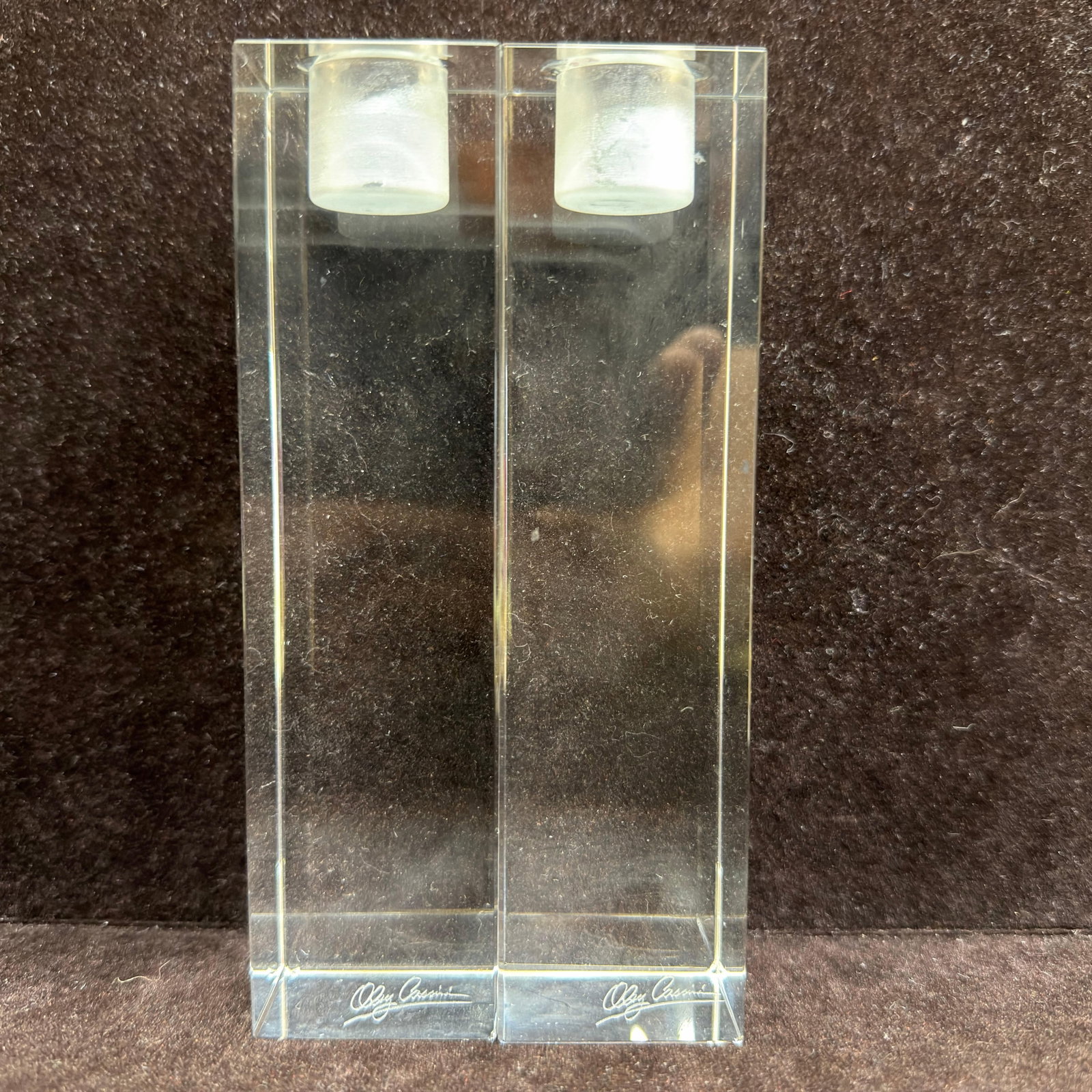 Pair of Oleg Cassini Crystal Glass Candlesticks Pillar Candle Holder: Pair of clear glass crystal-style candlesticks designed by Oleg Cassini. Each rectangular candlestick features a polished geometric form with a frosted candle cup and an engraved Oleg Cassini signatur