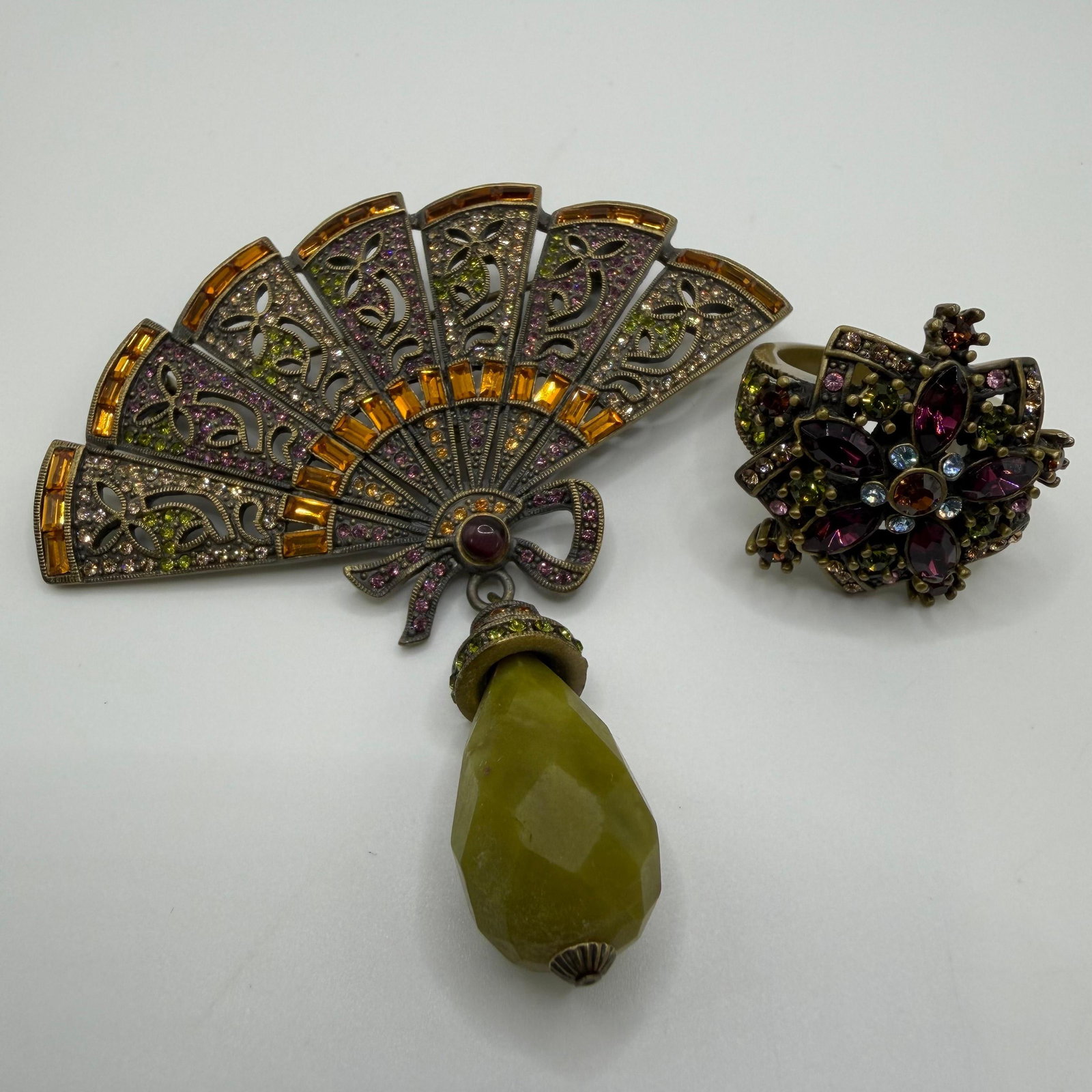 Heidi Daus Signed Crystal Fan Brooch and Floral Ring Jewelry Set: Heidi Daus designer costume jewelry set including a signed articulated fan brooch featuring multicolor crystals, amber-tone baguette accents, and a large faceted green teardrop dangle, together with a
