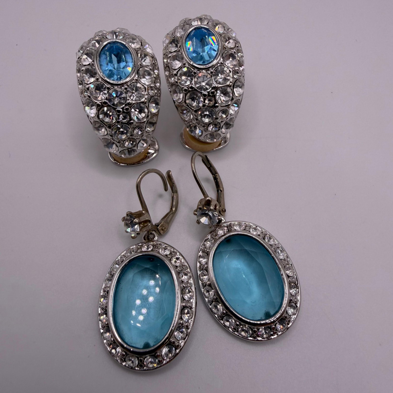 Nolan Miller Blue Crystal Costume Earrings Group Including Sterling Leverback Pair: Group of two pairs of Nolan Miller costume earrings featuring vibrant blue stones and clear crystal accents. Included is one pair of clip-on earrings with faceted blue center stones surrounded by clea