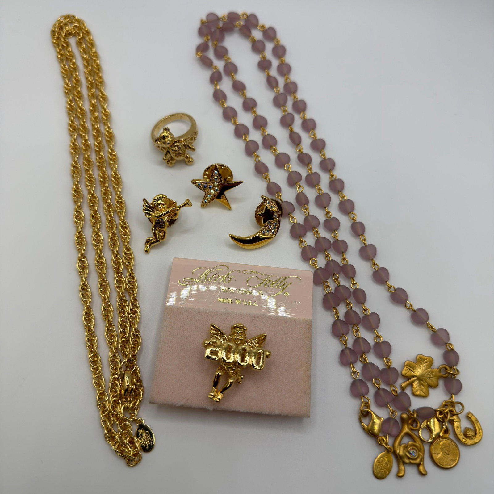 Kirks Folly Fairy Godmother Jewelry Group with Necklace Pins Ring Pin Set: Vintage Kirks Folly costume jewelry group including a Fairy Godmother pin on original Kirks Folly New York display card, lavender/pink frosted bead charm necklace with lucky charms, long gold-tone