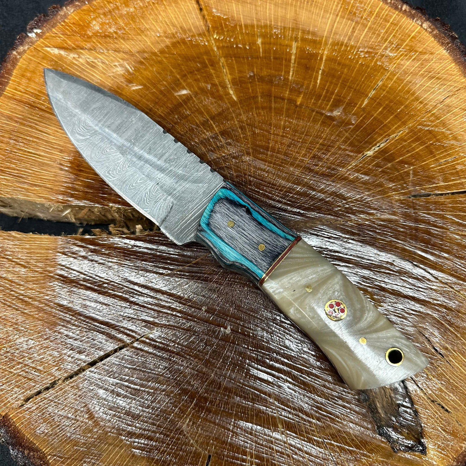MHS Cutlery Textured Fixed Blade Knife with Embossed Leather Sheath P94: Fixed blade knife by MHS Cutlery featuring a textured steel blade and decorative spine work. The handle has a contoured, multi-colored wood/epoxy resin-style grip with metal mosaic pin accents. Includ