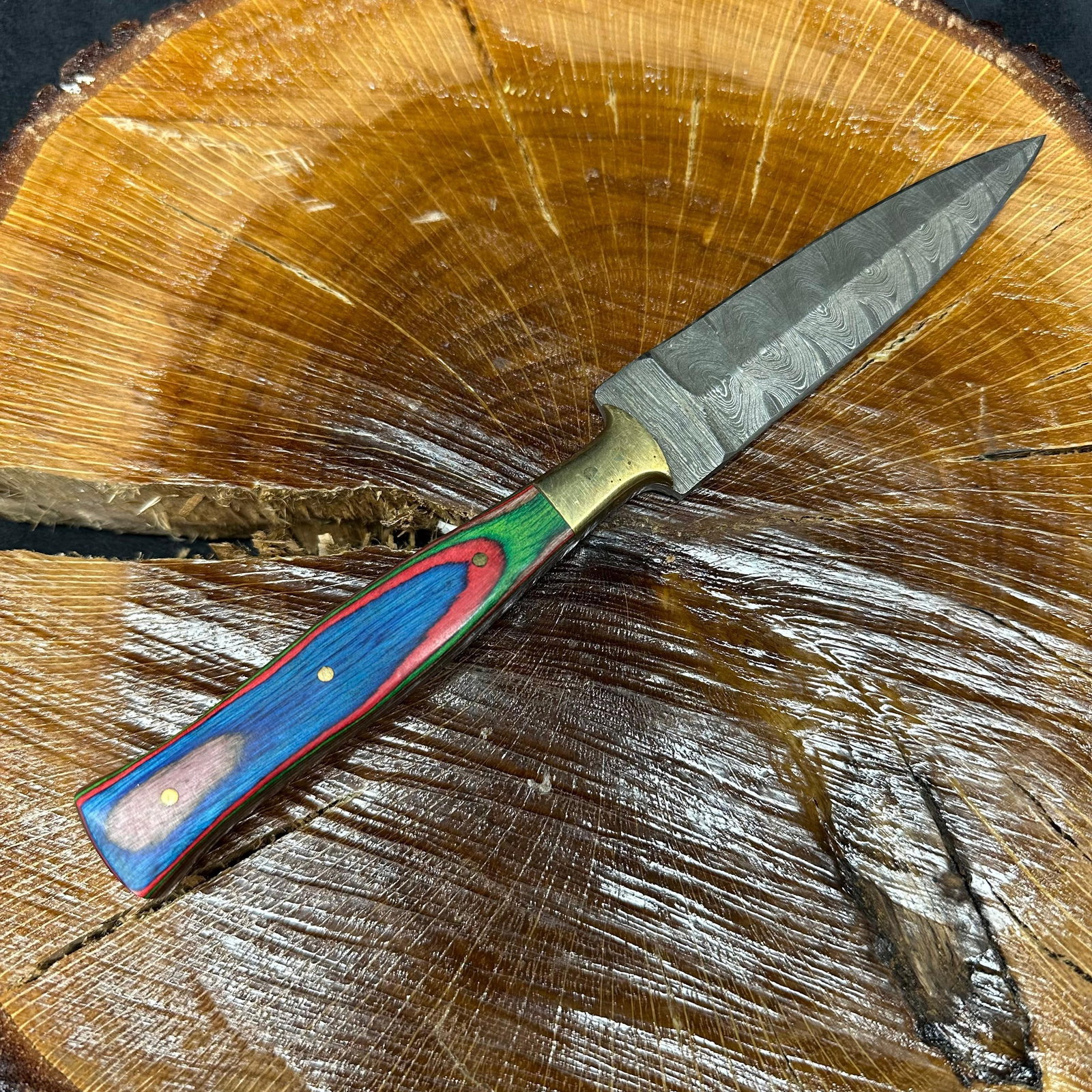 MHS Cutlery Fixed Blade Knife Spear Point Dagger Style P95: Fixed dagger-style blade knife by MHS Cutlery featuring a layered patterned steel blade and decorative spine work. The handle has a contoured, multi-colored wood/epoxy resin-style grip with metal mosa