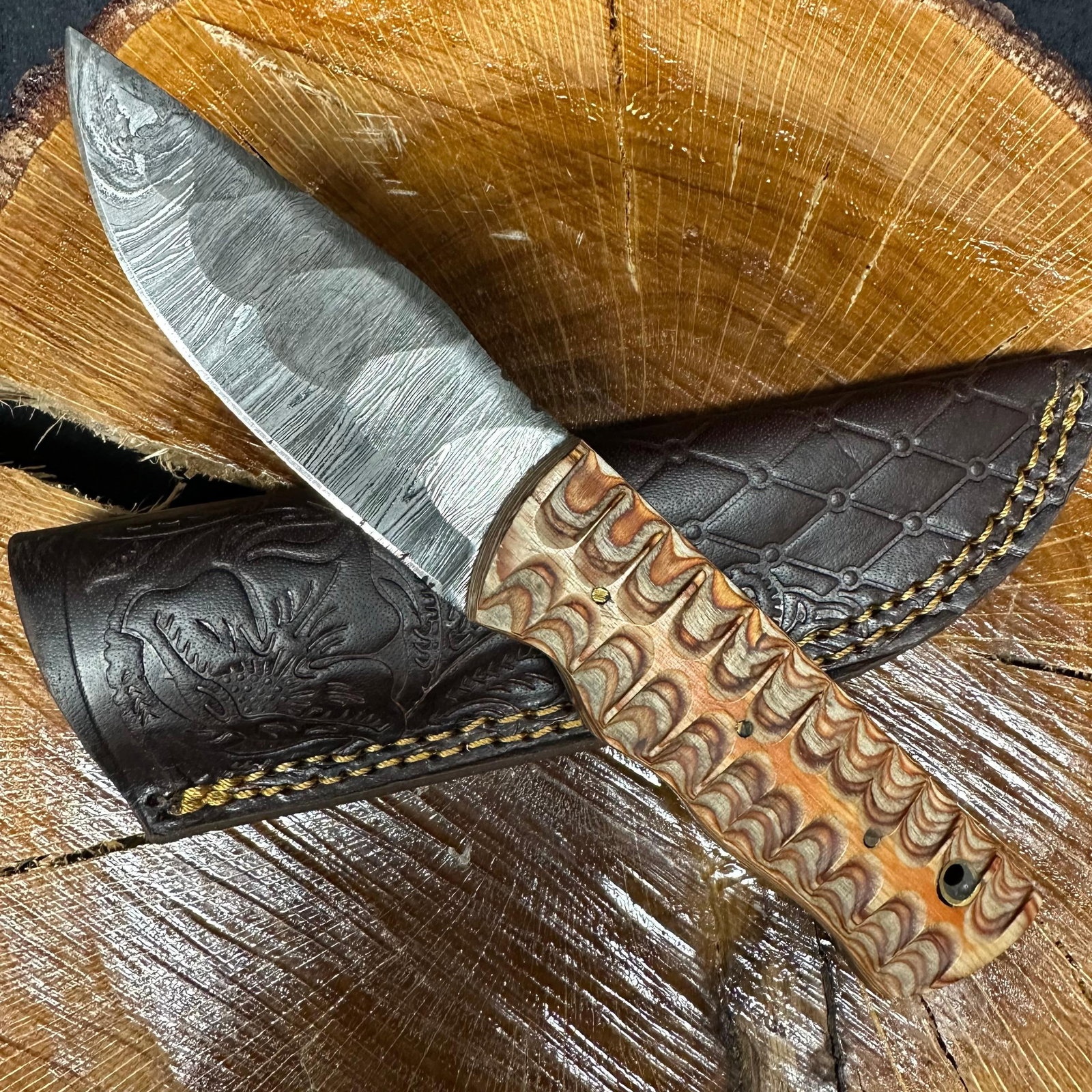 MHS Cutlery Steel Fixed Blade Knife with Carved Wave Style Handle P69: MHS Cutlery fixed blade knife featuring a patterned steel blade with visible layered steel grain. The blade has a pronounced drop-point profile and a sharpened cutting edge. The handle is crafted from