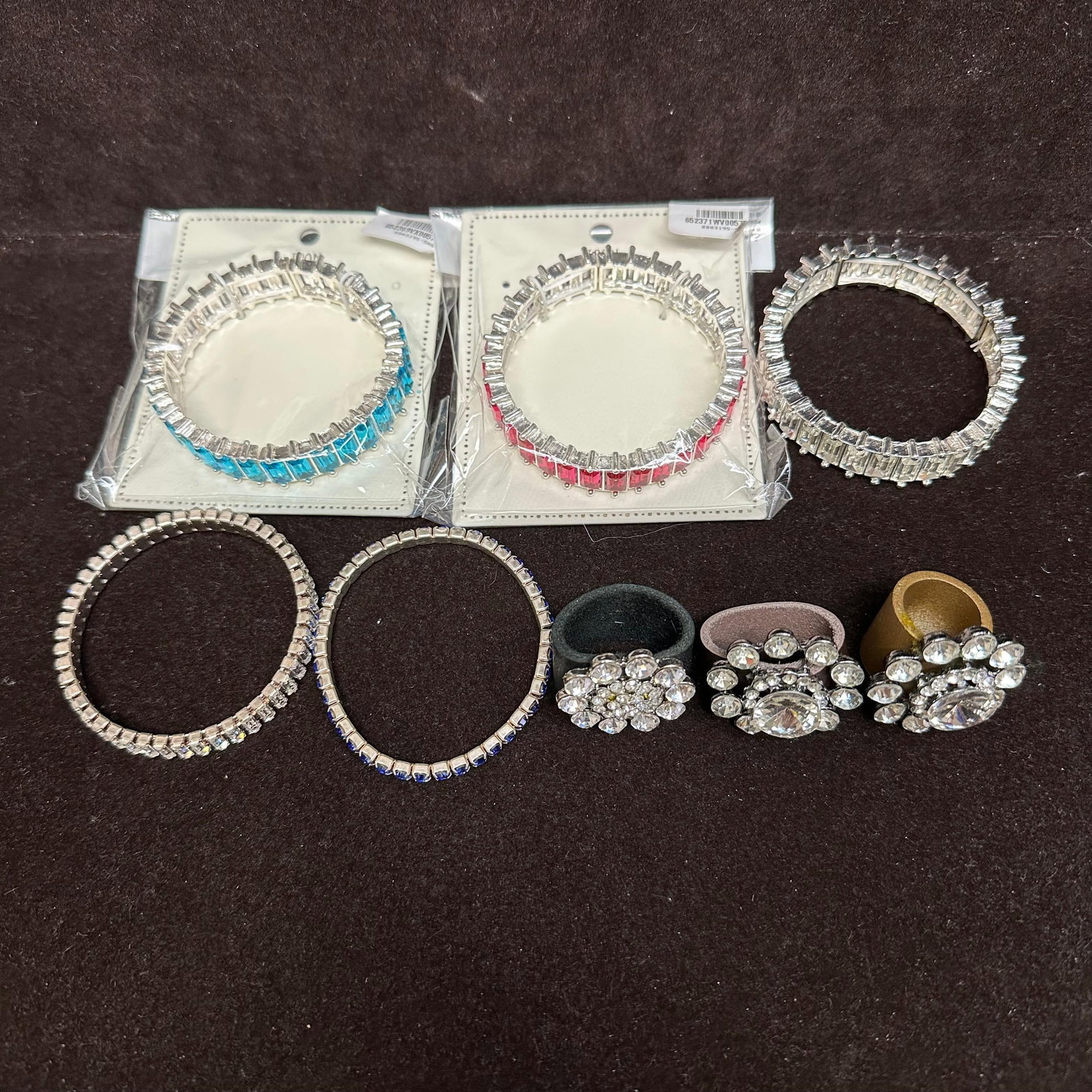 Costume Jewelry Bracelet And Ring Lot Rhinestone Stretch Bracelets: A group of costume jewelry, including multiple rhinestone stretch bracelets and three statement rings. Includes clear, blue, aqua, and fuchsia colored rhinestones. Some pieces retain original packagin
