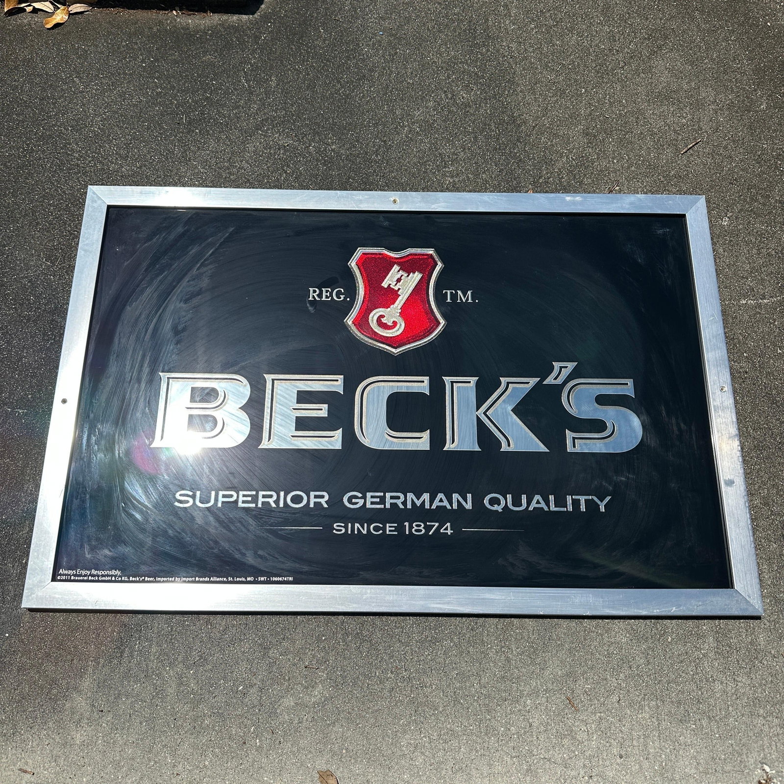 Becks Beer Framed Advertising Bar Mirror Sign Anheuser-Busch: Framed Beck’s Beer advertising mirror featuring the classic logo with red crest and “Superior German Quality Since 1874” slogan. Shows visible surface wear, with drill holes pre
