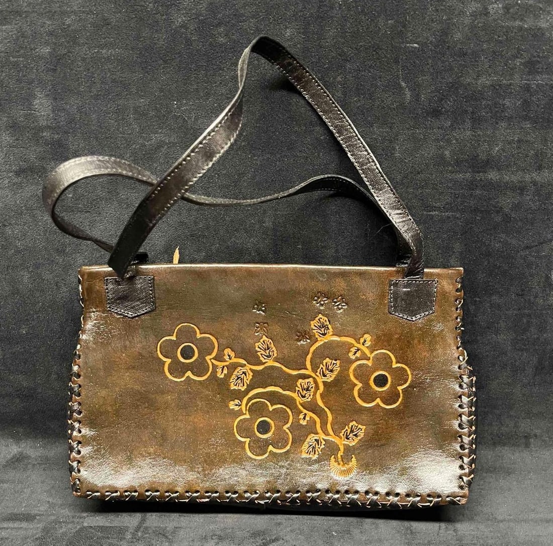 Vintage Leather Handicraft Purse With Embossed Flowers (8): This lot contains a Vintage Leather Handicraft Purse With Embossed Flowers (8). The bag is hand-stitched and has a very soft leather liner and inside zipper pocket. It is approx 12" x 2 1/2" x 8" and