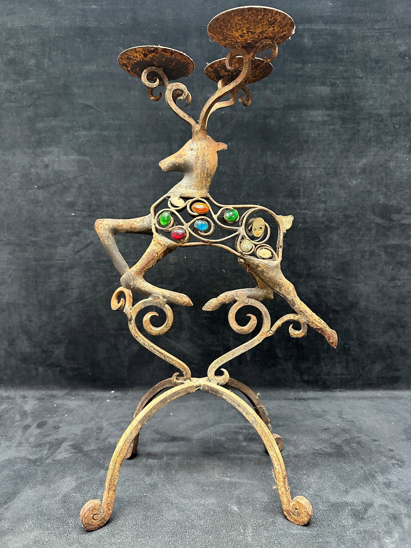 Wrought Iron Deer Form Candelabra Colored Glass Cabochons: Pier 1 wrought-iron metal figural deer-form candelabra featuring three candle holders and colored-glass cabochon accents. Decorative scroll work design with aged patina and oxidation throughout