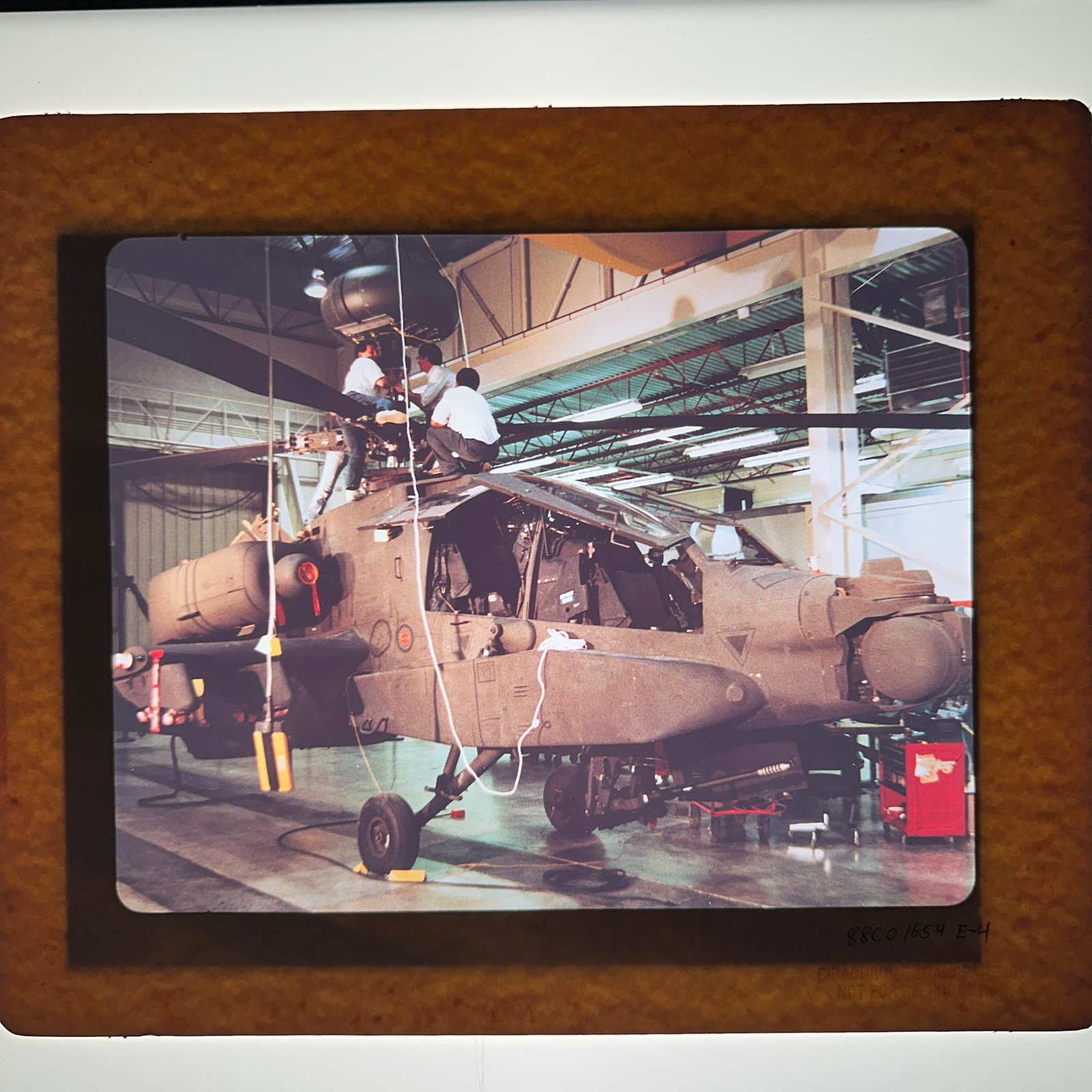 Military Test Facility And AH-64 Apache Film Transparency Slide Collection: Group of vintage color photographic film transparency slides featuring military and aerospace subjects, including an AH-64 Apache attack helicopter, camouflage-covered armored vehicle, radar or sensor