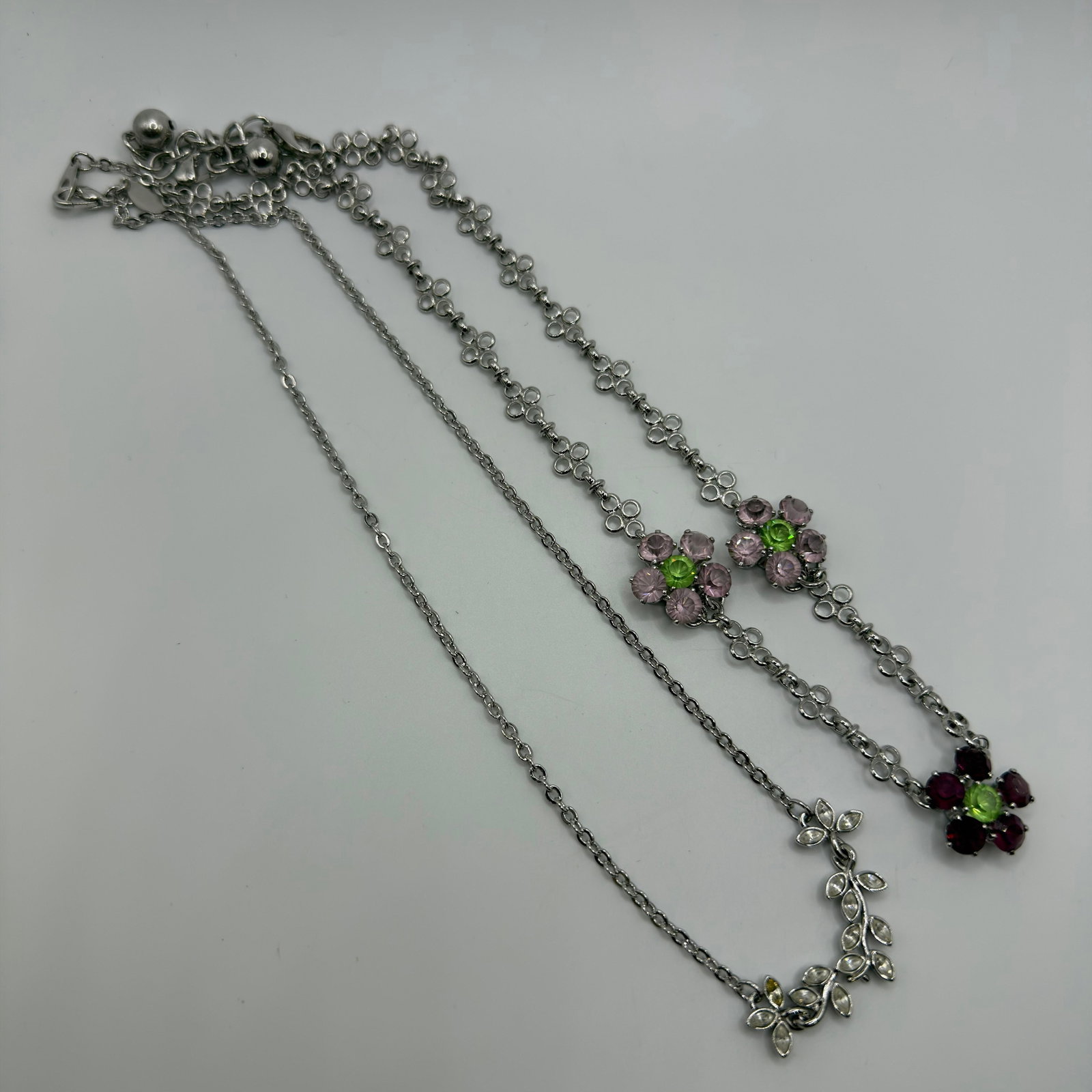 Nolan Miller Silver Tone Floral Necklace Pair HG65: Both jewelry pieces marked Nolan Miller, featuring a floral design with rhinestone crystal accents. These items are pre-owned, with light wear, minor imperfections, and surface scratches. Please refer