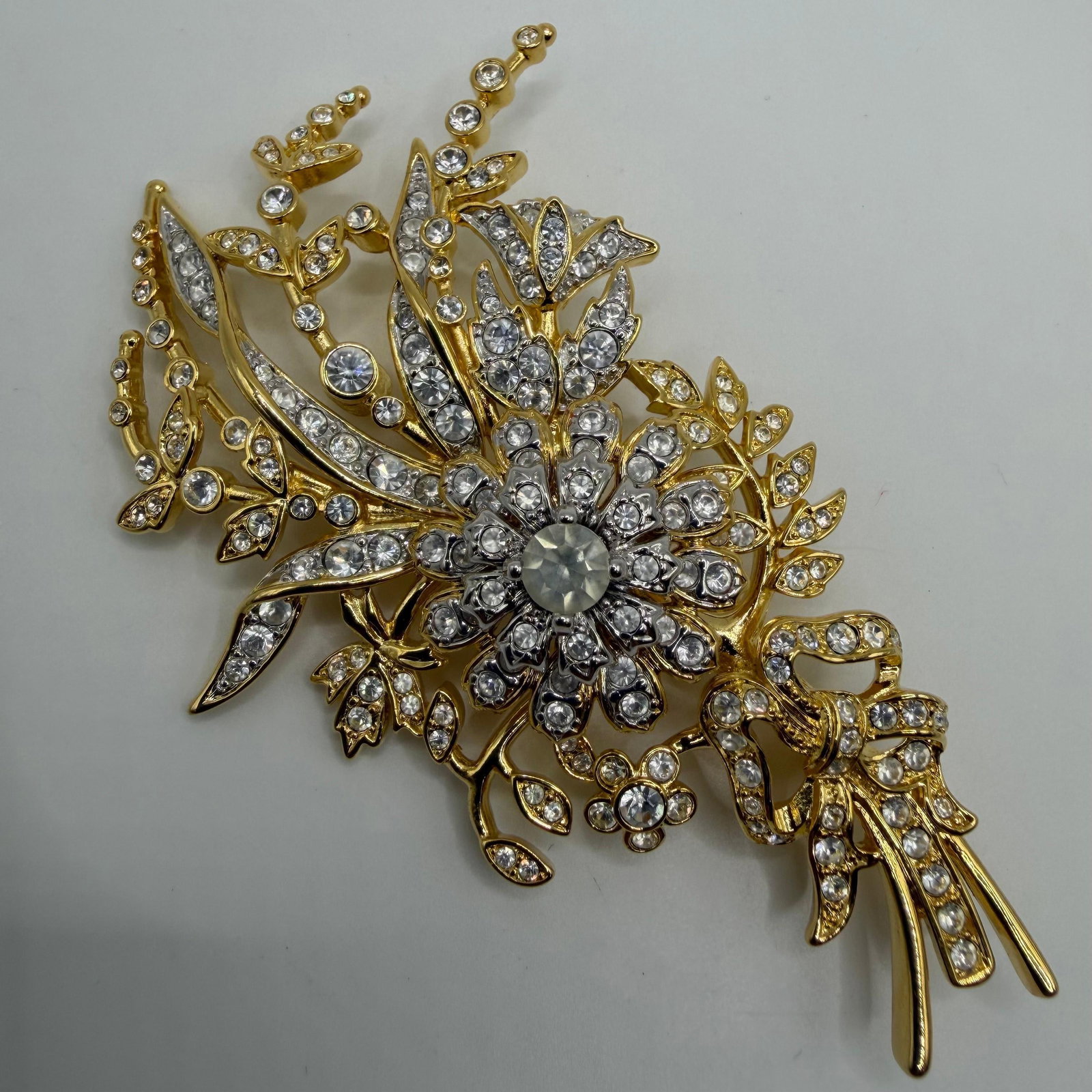 Nolan Miller Crystal Floral Bouquet Large Statement Brooch: Large signed Nolan Miller statement brooch featuring an elaborate floral bouquet design with a gold-tone finish accented by numerous clear faceted crystals. The dimensional openwork design includes a 