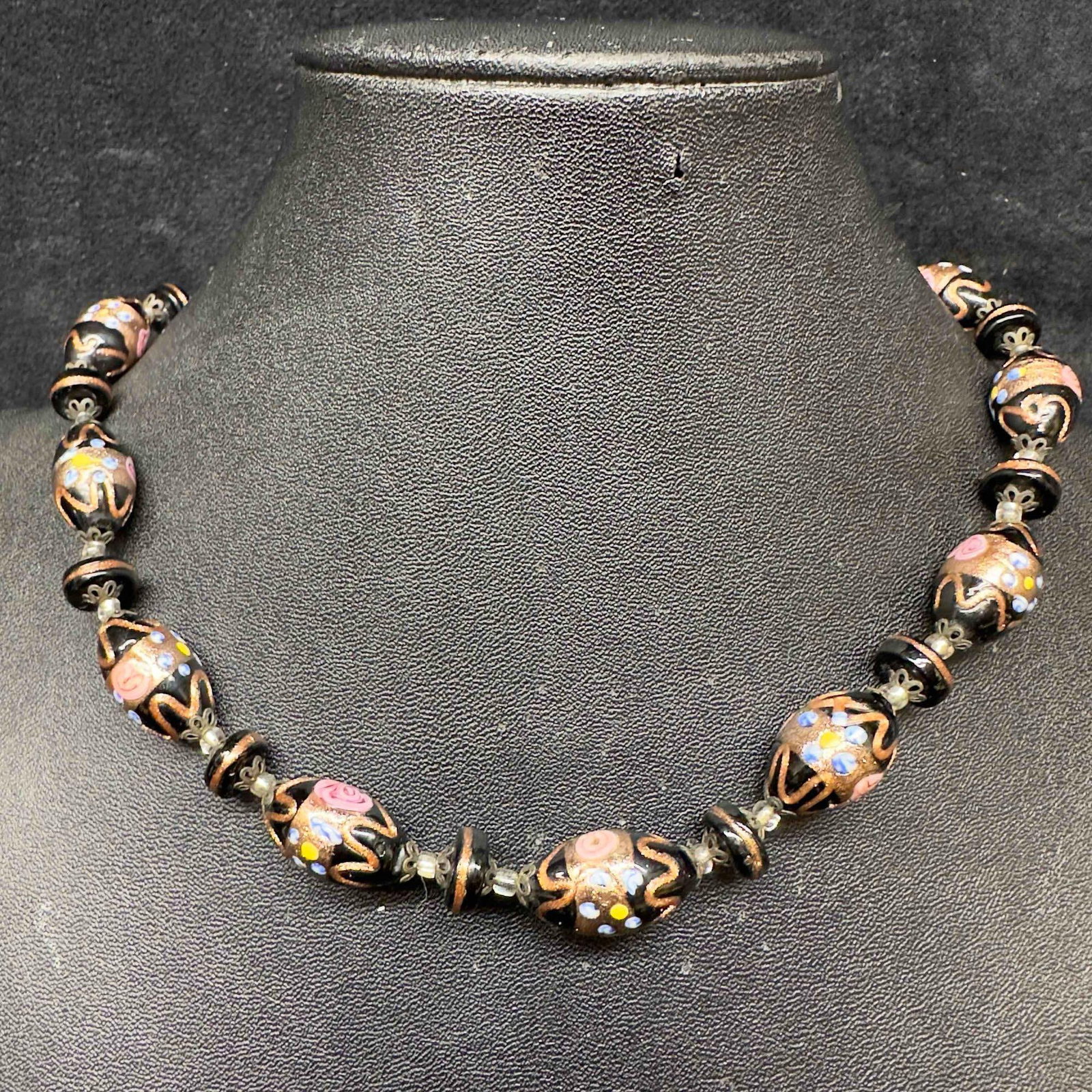 Murano Venetian Lamp Work Art Glass Floral Copper Black Oval Beaded Necklace C75: Murano Venetian Lamp Work Art Glass Floral Black Oval Beaded Necklace C75. Necklace with black colored glass beads with beautiful designs on each. The necklace features floral and copper colored accen