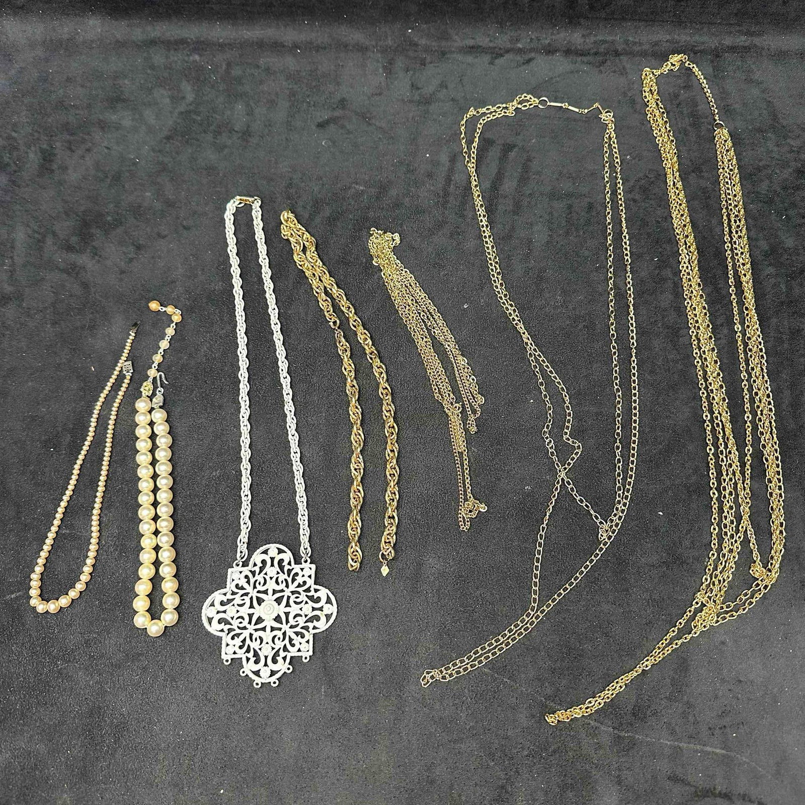 Costume Necklace Lot Simulated Pearls Gold and Silver Tone Chains Oversized Pendant White: Collection of vintage costume necklaces including a simulated pearl necklace with rhinestone clasp, single strand faux pearl necklace, large white filigree pendant on chain, multiple gold tone and sil