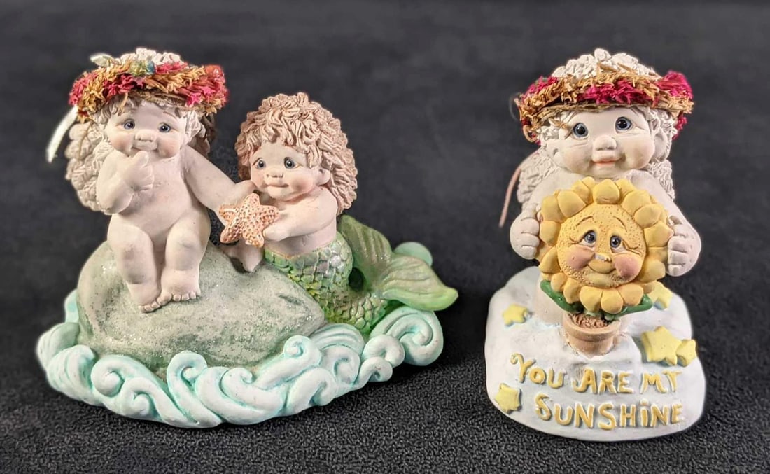 Two Dreamsicle Figurines Mermaid And Sun: This lot includes: (1) Mermaid's Gift. This is approx 5" x 2 1/2" x 4 1/2". (1) You Are My Sunshine This is approx 2 1/2" x 2 1/2" x 4". Both are in a good,
