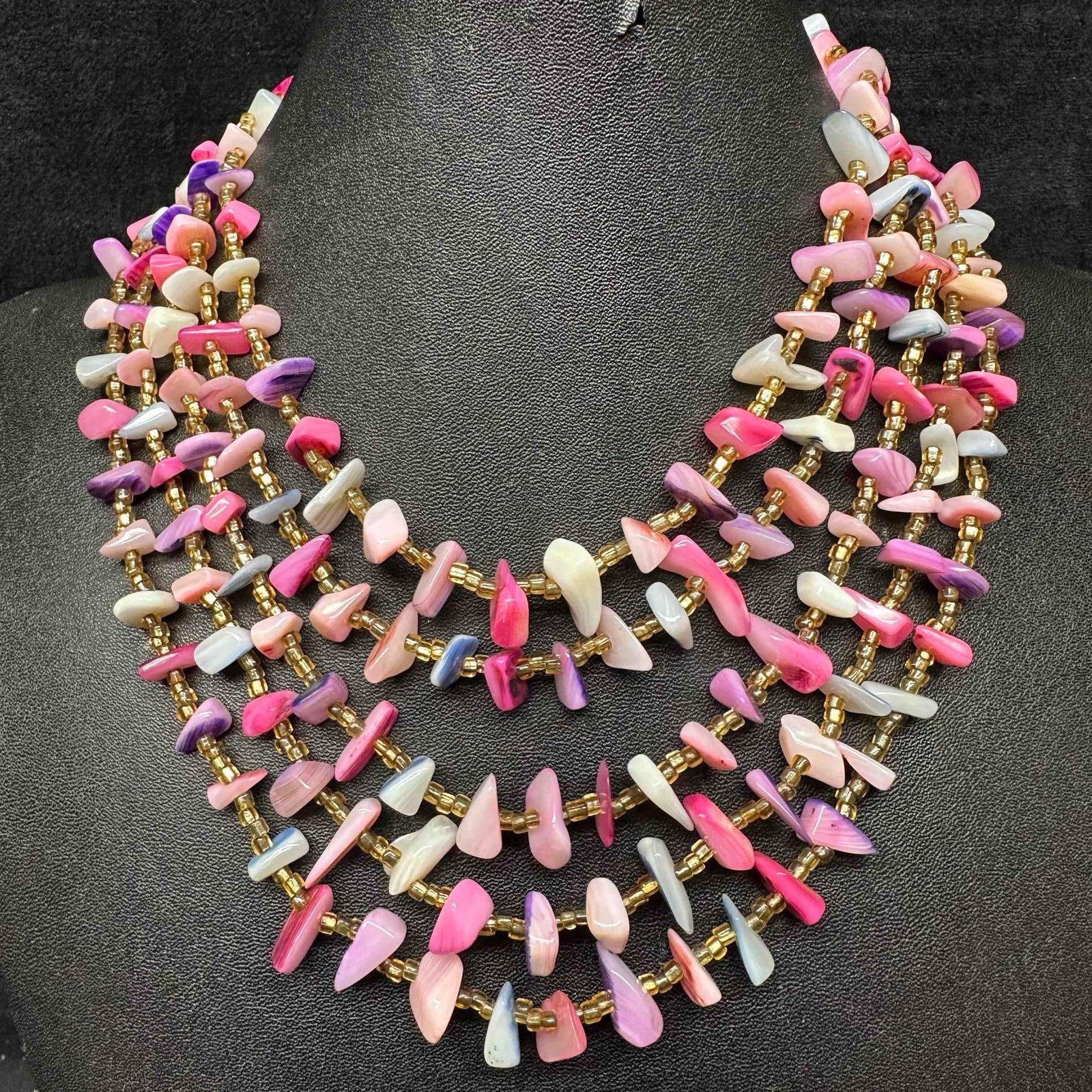Pink and Purple MOP Abalone Shell Multi Strand Choker Necklace: Necklace with purple and pink colored MOP abalone shell unique shaped beads with beautiful designs on each. The necklace features yellow and gold colored accents. The necklace features a open box styl