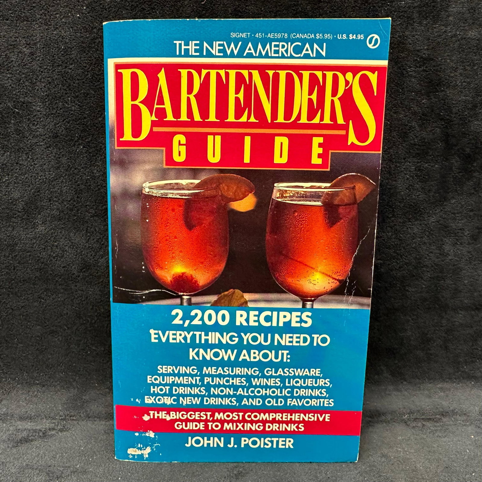 The Bartender's Guide Book Signed by John J. Poister Softcover: Signed by John J. Poister with a personal inscription dated 1989 to Michel Roux. Condition shows general handling wear, scuffing, and surface marks to the cover consistent with age. Interior pages