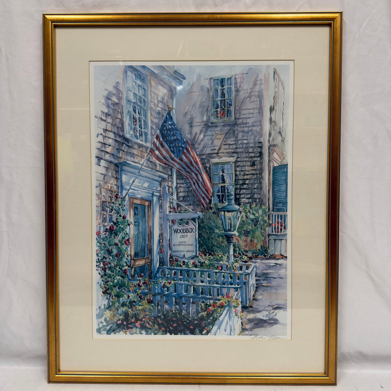 William Welch Signed Print Woodbox Inn Nantucket Patriot Scene: Art print after an original watercolor by William Welch, depicting the historic Woodbox Inn 1709 Guest Accommodations with an American flag and garden setting. Pencil signed by the artist in the 