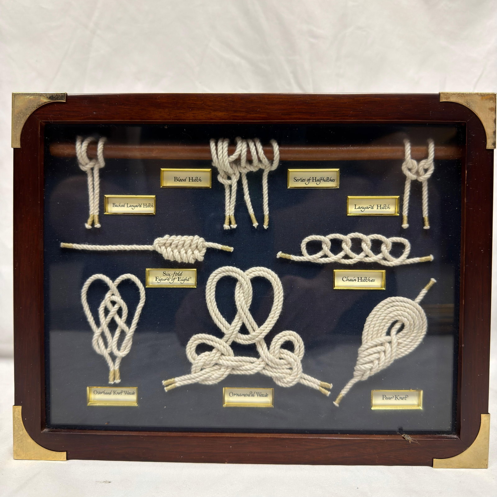 Framed Decorative Sailor Nautical Rope Knot Display Shadow Box: Framed shadow box featuring a collection of traditional nautical rope knots and hitches, each identified with engraved labels including Becket Lanyard Hitch, Blood Hitch, Lanyard Hitch, Chain