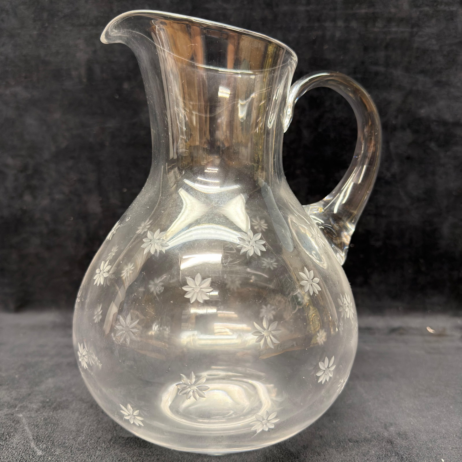 Tiffany and Co. Etched Floral Flower Style Pattern Glass Pitcher: Clear glass pitcher featuring an elegant bulbous body, applied loop handle, flared pouring spout, and an allover acid-etched floral daisy pattern. Acid-etched "Tiffany & Co." mark to the u