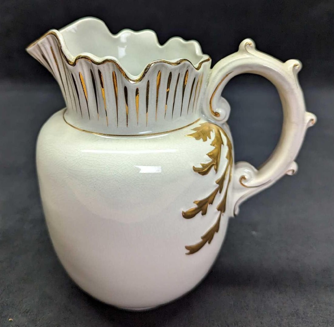 White Ironstone Porcelain Gold Accents Pitcher: White Ironstone Porcelain Gold Accents Pitcher. This is approximately 7" x 5" x 7" and it weighs 1.19lb. The pitcher has crazing, markings, and there is a small hole near the bottom. There might have 