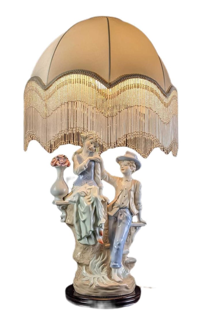 Unique Vintage Porcelain lamp: This very unique Porcelain lamp shows two young teens as they avoid the rain under a rather large umbrella. They sit upon an old wall with a vase and wait for the rain to finish. This resembles a Llad