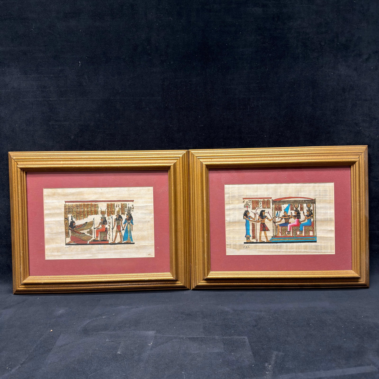 Pair of Hand-Painted Egyptian Papyrus Paintings in Framed Presentation: Pair of hand-painted Egyptian papyrus artworks depicting traditional scenes inspired by ancient Egyptian mythology and hieroglyphics. Executed on genuine papyrus and professionally matted in matching 