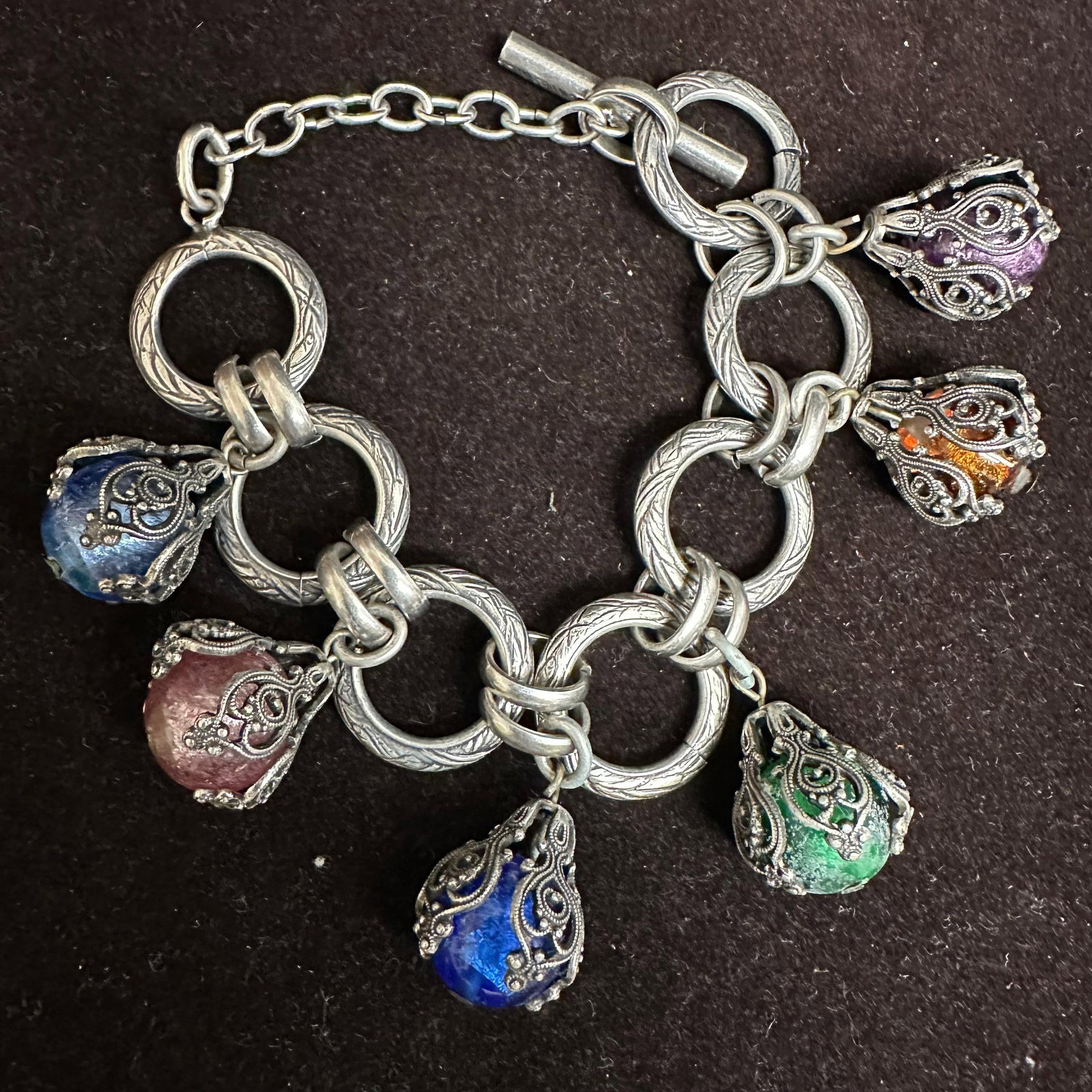 French Style Multi Colored Poured Glass Foil Charm Dangle Bracelet France: French Style Multi-Color Poured Glass Dangle Foil Charm Bracelet. No identifying markings. Necklace with multiple colored glass beads with beautiful designs on each. The necklace features foil ac
