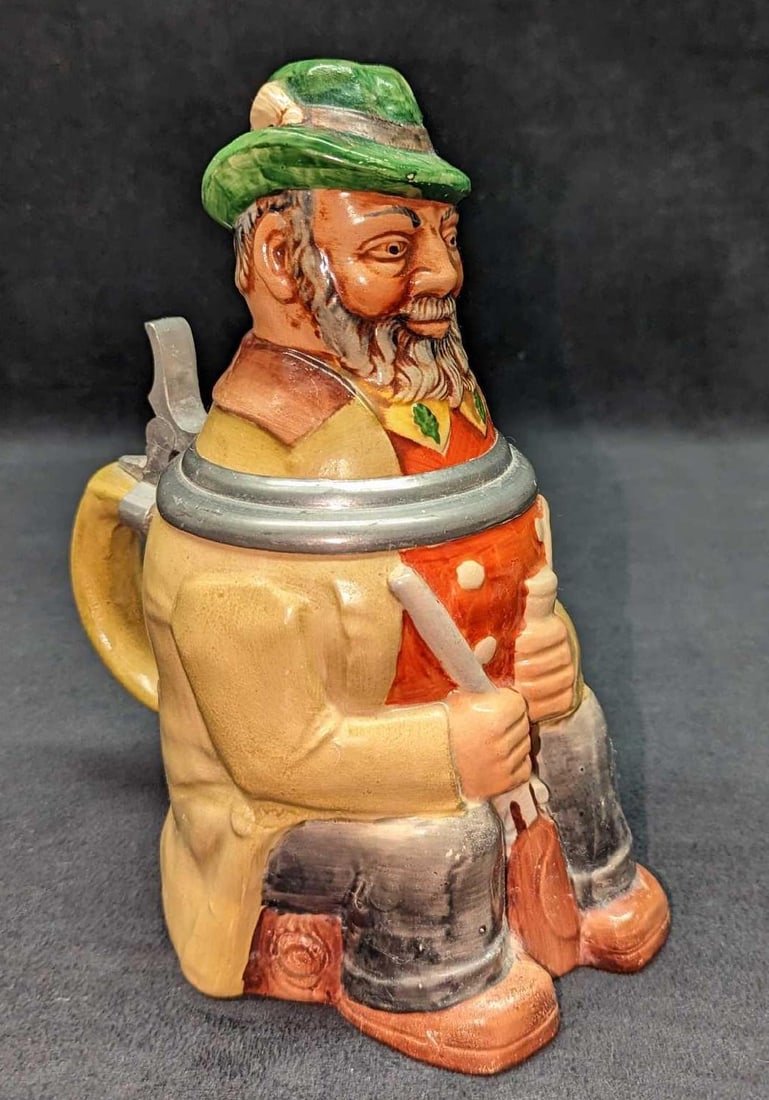 Vintage West German Hunter Man With Pipe: Vintage West German Man With Accordion Stein. This lidded ceramic stein is approx 5" x 6 3/4" x 8 3/4" and it weighs 2.25 lbs. The stein is in a good, vintage condition with no chips or cracks. There 