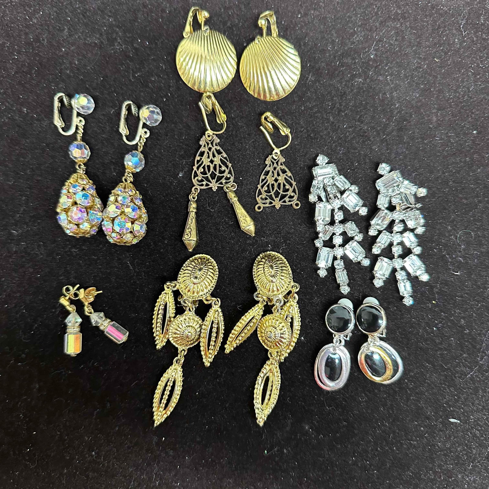 Costume Jewelry Earrings Lot of Seven Pairs Assorted Styles Rhinestones Gold Tone: Collection of seven pairs of vintage costume earrings in assorted styles and materials. Includes gold-tone shell clip-ons, filigree dangle earrings, rhinestone drop earrings, statement chandelier styl