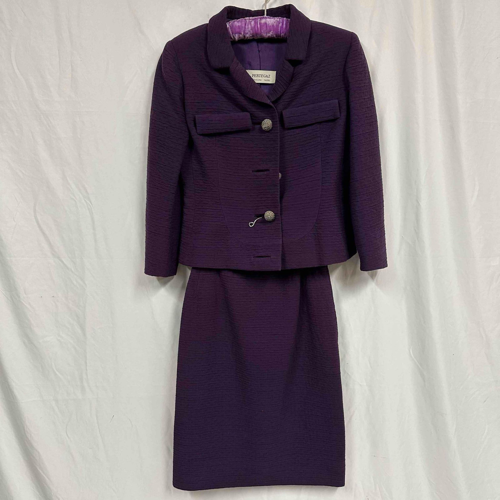 Manuel Pertegaz Barcelona Madrid Purple Skirt Suit Jacket: Four button closure with no pockets. The suit includes a jacket with a button closure and two decorative pockets, paired with a knee-length skirt. Overall the skirt suit is in good condition, with