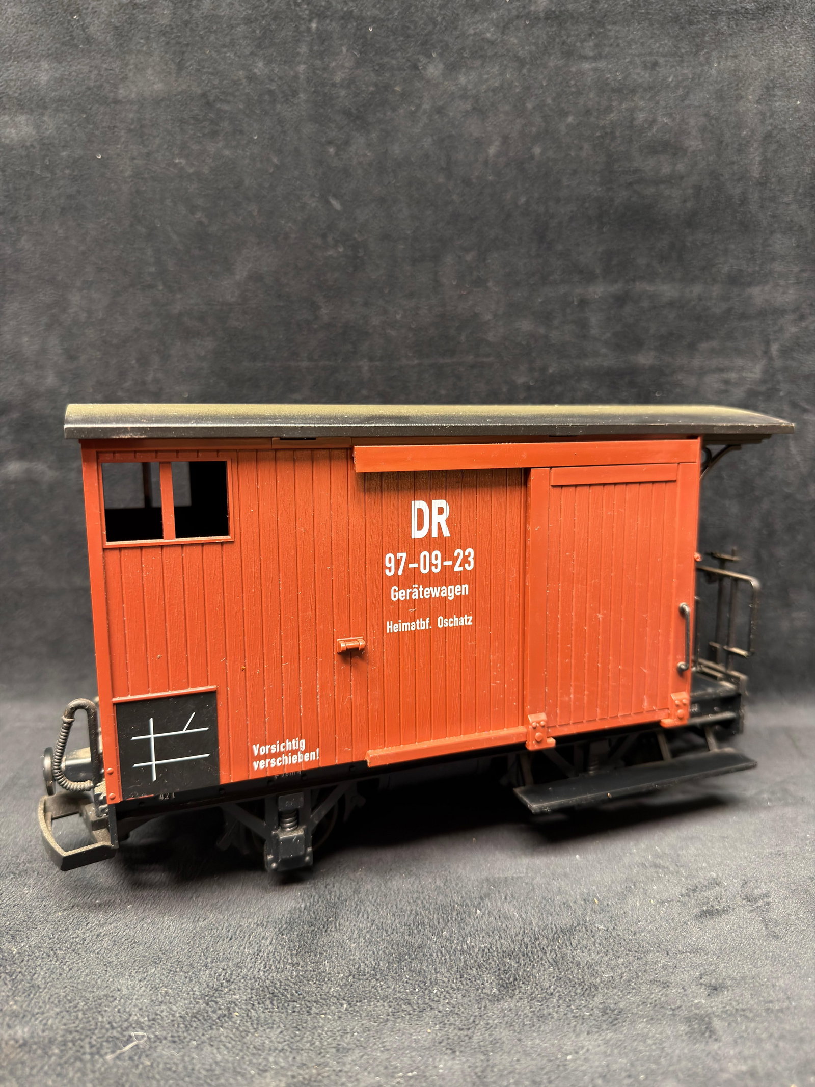 LGB G Scale DR 97-09-23 German Baggage Car: LGB G scale Deutsche Reichsbahn DR 97-09-23 Geratewagen baggage/equipment car in red-brown finish. Features operating sliding side doors, end platforms, detailed undercarriage, and metal wheels. Pre-o