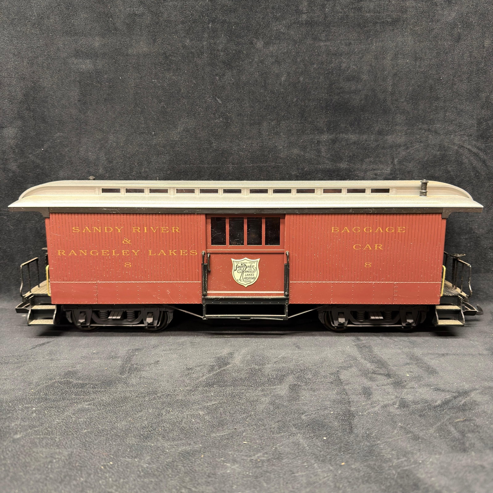 LGB 33840 G Scale Sandy River and Rangeley Lake Baggage Car #8 Lehmann: G-scale Sandy River & Rangeley Lakes Railroad baggage car #8 in red/brown with a gray/silver roof. Features sliding baggage doors, detailed trucks, end platforms, railings, and couplers. Marked LG