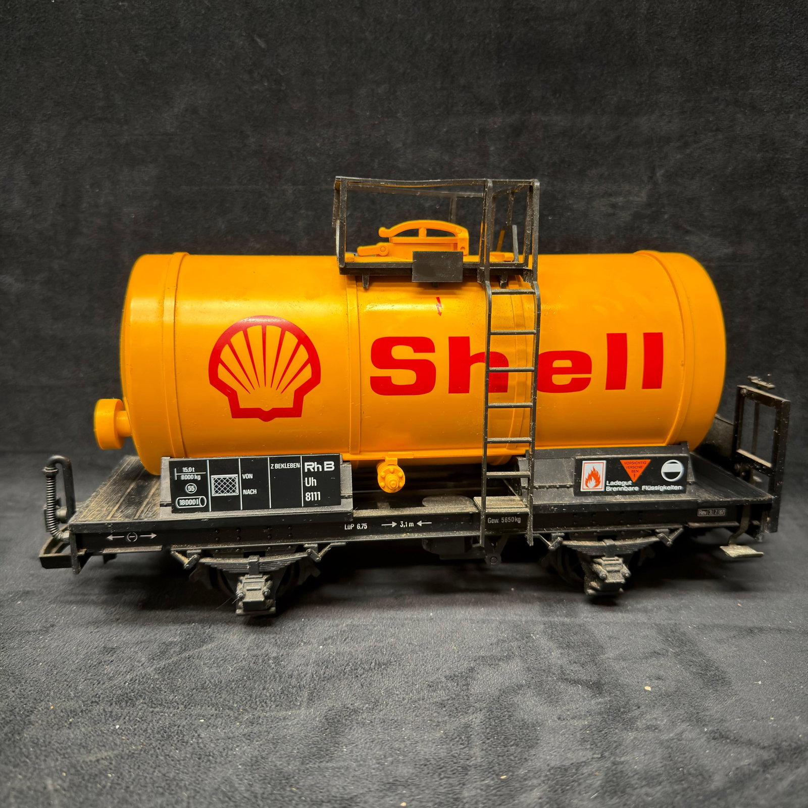 LGB Shell Tank Car G Scale Model Train Yellow: LGB G-scale Shell tank car featuring a yellow tank with red Shell graphics, black chassis, ladder, upper platform, and detailed wheel assemblies. Marked LGB by Lehmann on the underside. Pre-owned with