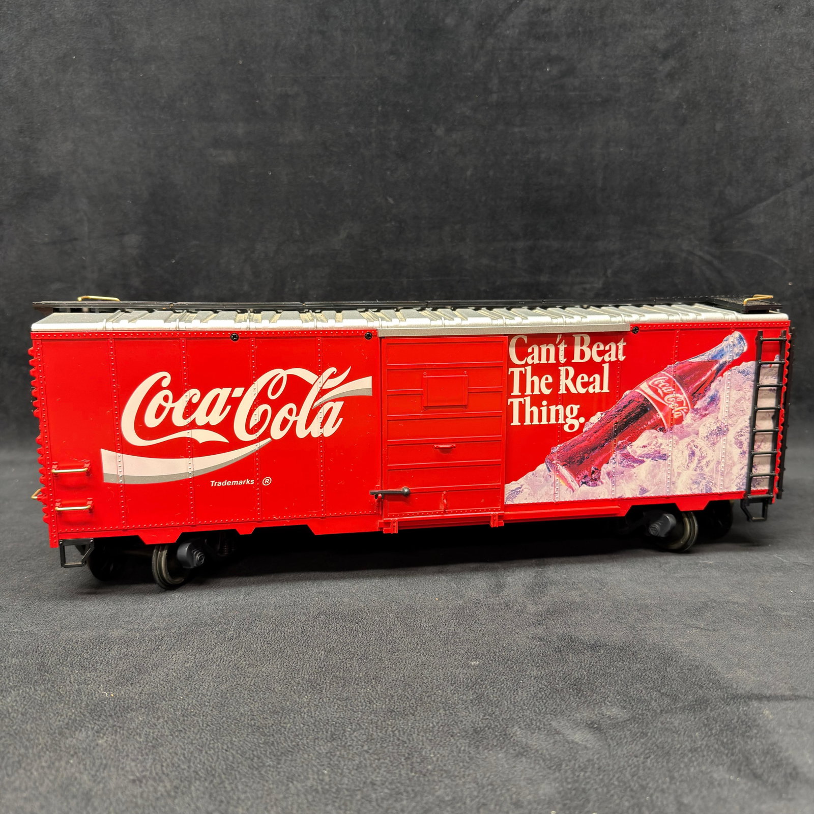 LGB Coca-Cola Can’t Beat The Real Thing G Scale Boxcar Red: LGB Coca-Cola G scale boxcar featuring bright red Coca-Cola graphics with “Can’t Beat The Real Thing” advertising and a bottle-on-ice design. Detailed trucks, plastic wheels, and an 
