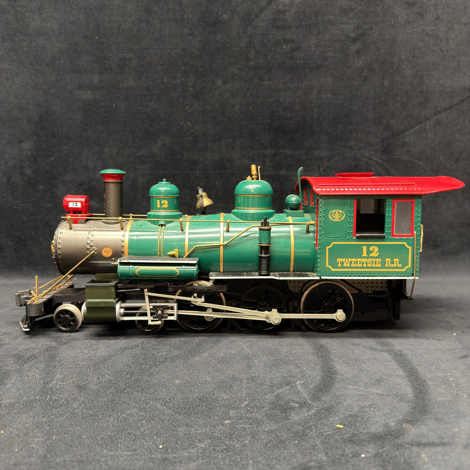 Bachmann Tweetsie Railroad No. 12 G Scale Steam Locomotive Big Haulers: Large G-scale Tweetsie Railroad No. 12 steam locomotive in a green, red, and gold finish with a detailed boiler, bell, piping, running gear, metal wheels, and cab interior. Modeled after the historic 