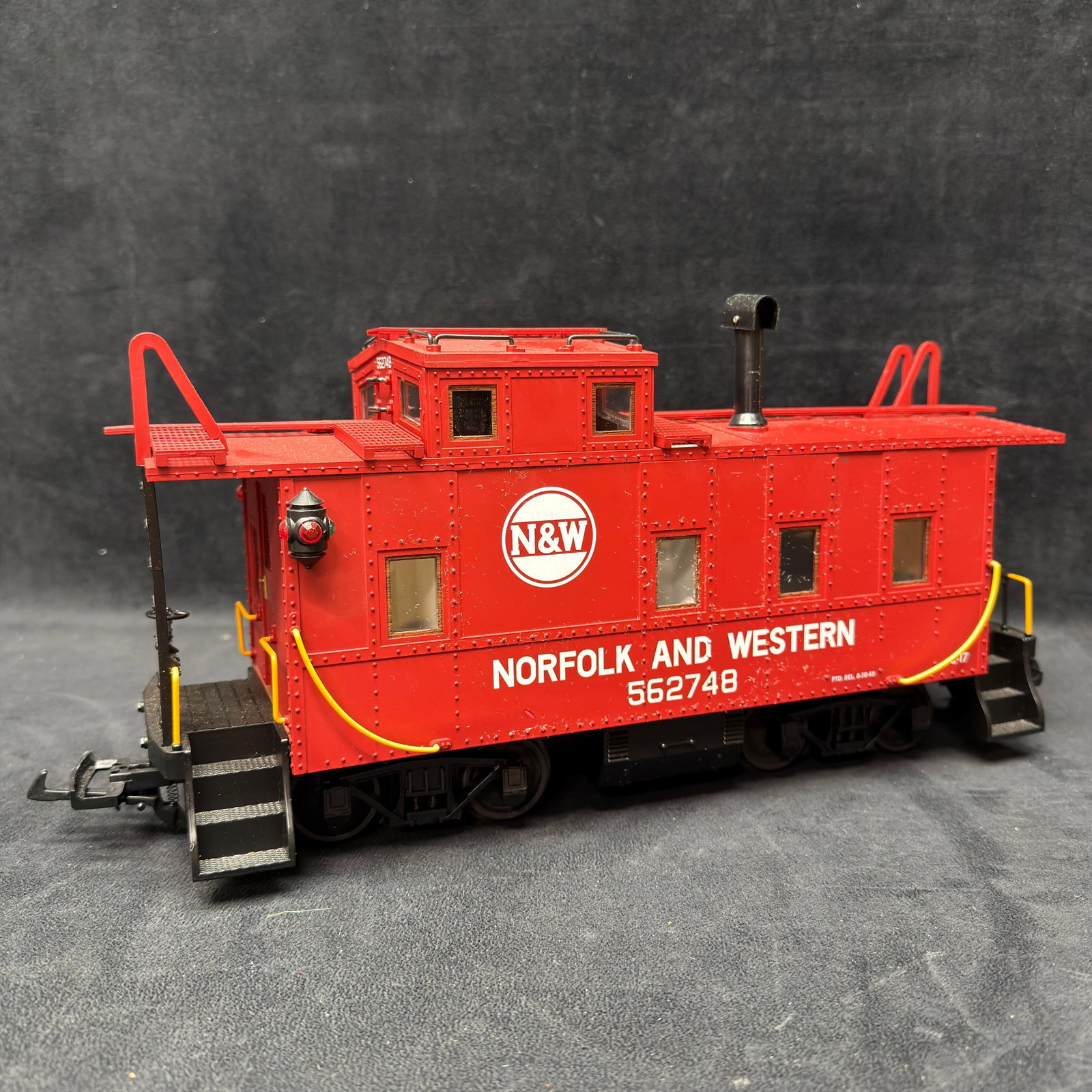 Norfolk and Western NW 562748 G Scale Caboose Red: Large G-scale Norfolk and Western red caboose, road number 562748, featuring N&W logos, cupola, end platforms, ladders, handrails, marker lights, and metal wheels. Electronics have not been tested