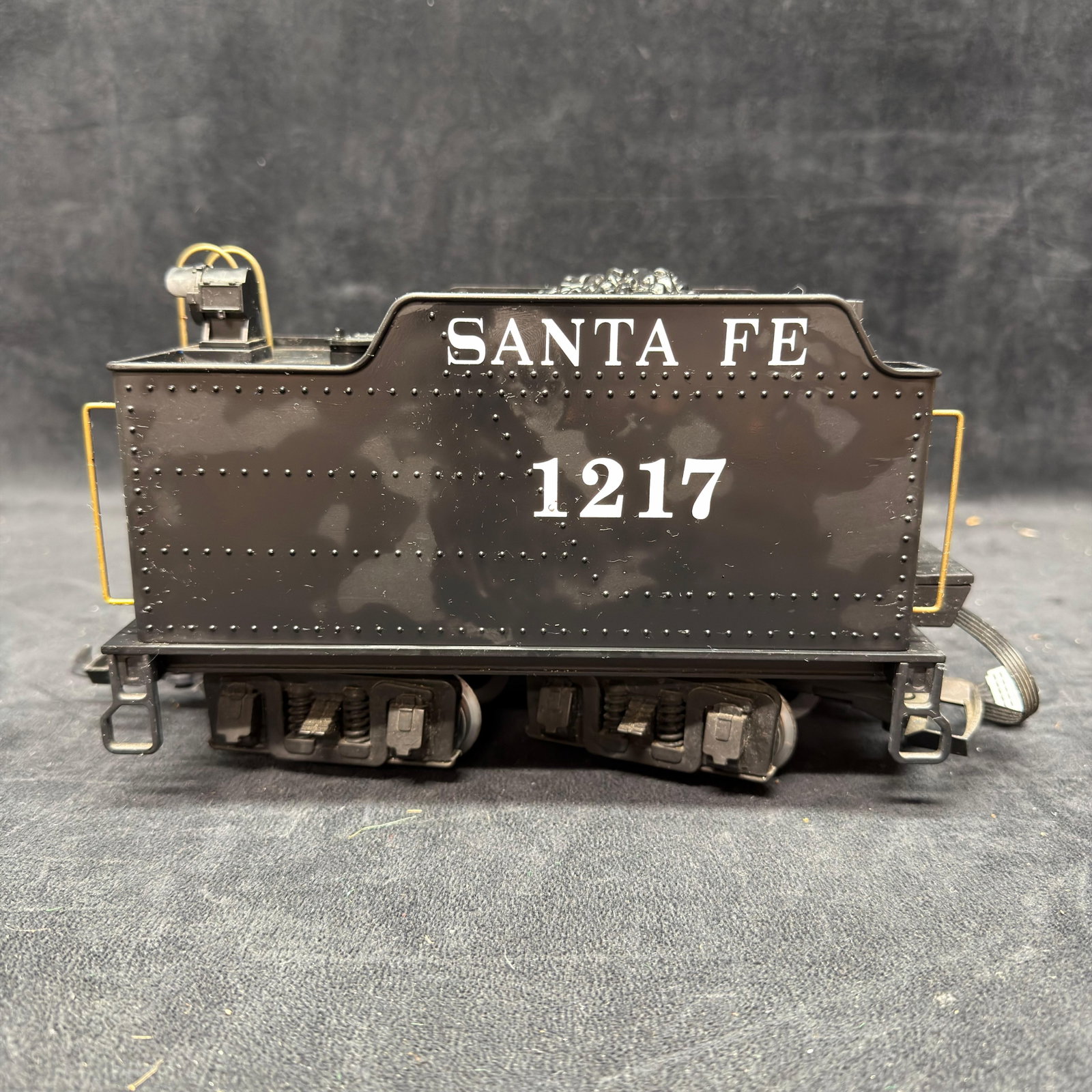 Santa Fe No. 1217 G Scale Locomotive Tender LGB: G scale Santa Fe locomotive tender, road number 1217, finished in black with white lettering. Features simulated coal load, rear light, yellow handrails, detailed trucks, metal wheels, and electrical 
