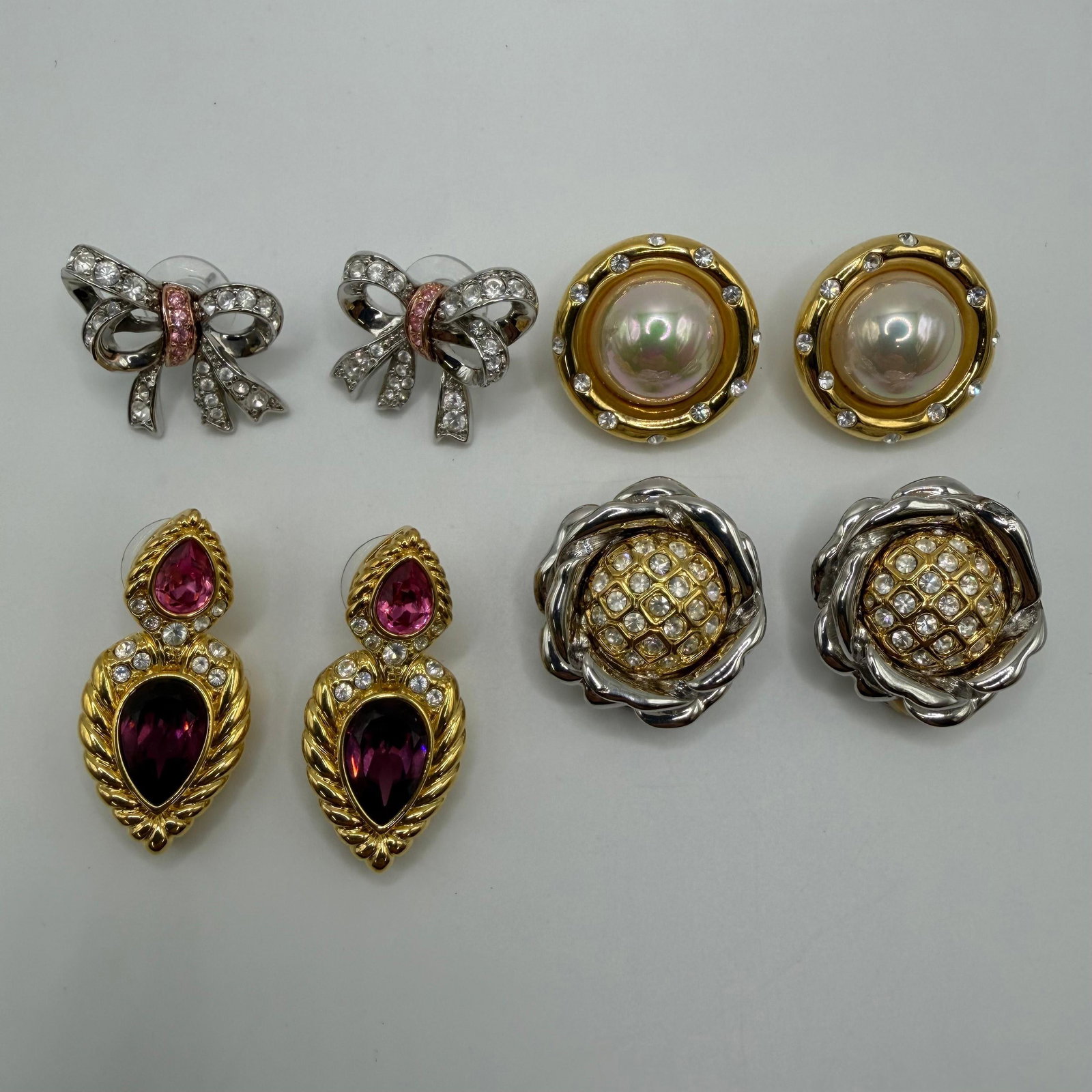 Four Pairs of Nolan Miller Designer Costume Earrings Faux Pearl Crystal and Rhinestones Accents: Collection of four pairs of Nolan Miller designer costume earrings in gold-tone and silver-tone finishes. Includes a pair of rhinestone bow earrings with pink crystal accents, a pair of faux pearl and