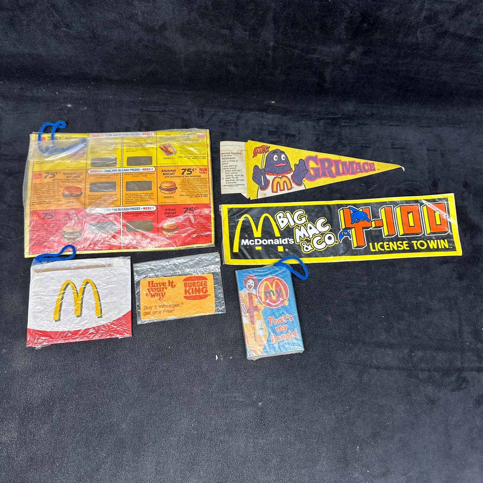 Burger King and McDonald's Promotional Ephemera Lot Grimace Pennant Big Mac Coupons Paper: A group of vintage fast-food promotional ephemera primarily featuring McDonald’s, with one Burger King piece included. Lot includes assorted paper and plastic advertising items such as a Grimace