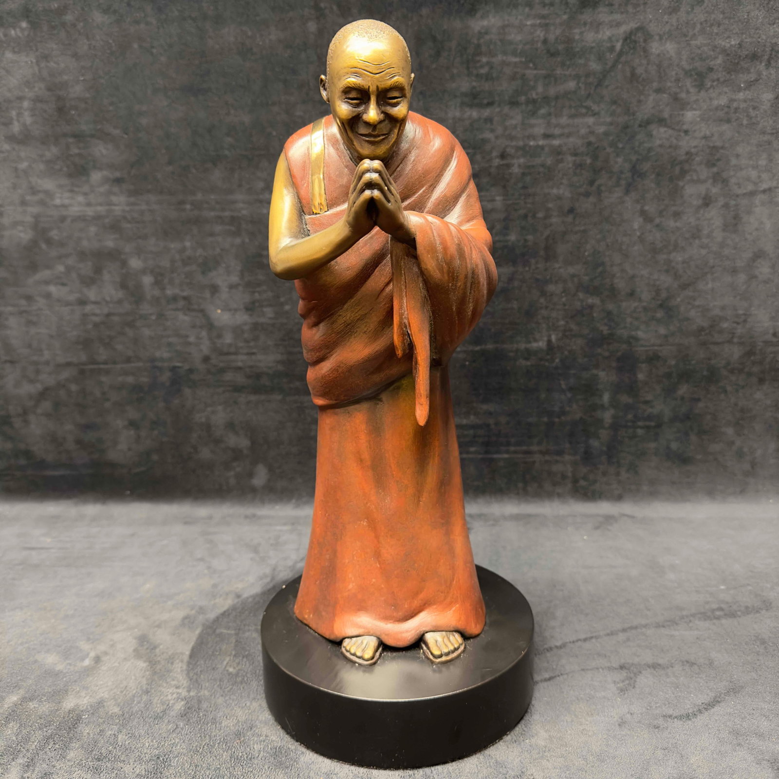 Dalai Lama Praying Bronze Sculpture Statue: Dalai Lama Praying Bronze Sculpture Statue. Medium bronze statue featuring Dalai Lama in a prayer pose with a red garment and gold accents. Black velvet felt bottom. Etched JB on