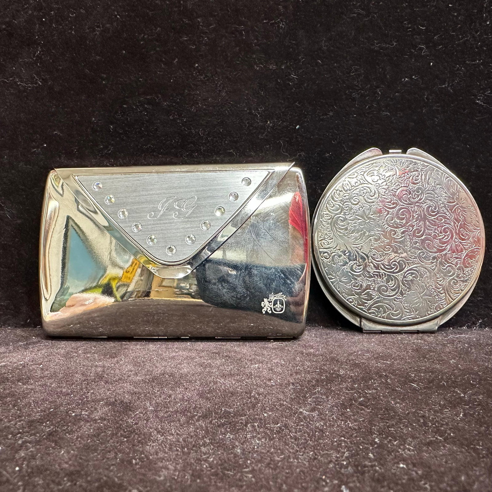 Colibri of London Silver-Tone Cigarette Case and Engraved Compact Mirror: Matching pair of silver-tone personal accessories by Colibri of London. Includes a hinged cigarette case with mirrored interior, spring clip marked Colibri of London, and an exterior geometric flap de