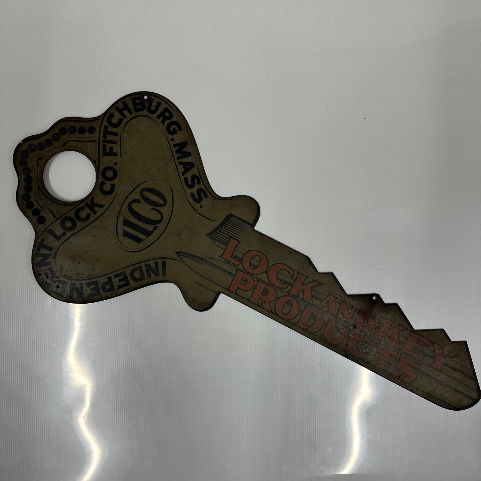 ILCO Hardware Store Lock And Key Products Tin Litho Sign: Vintage die-cut litho tin advertising sign in the form of a large key for Independent Lock Co., Fitchburg, Massachusetts. The sign features bold printed graphics, including the ILCO and the slogan Loc