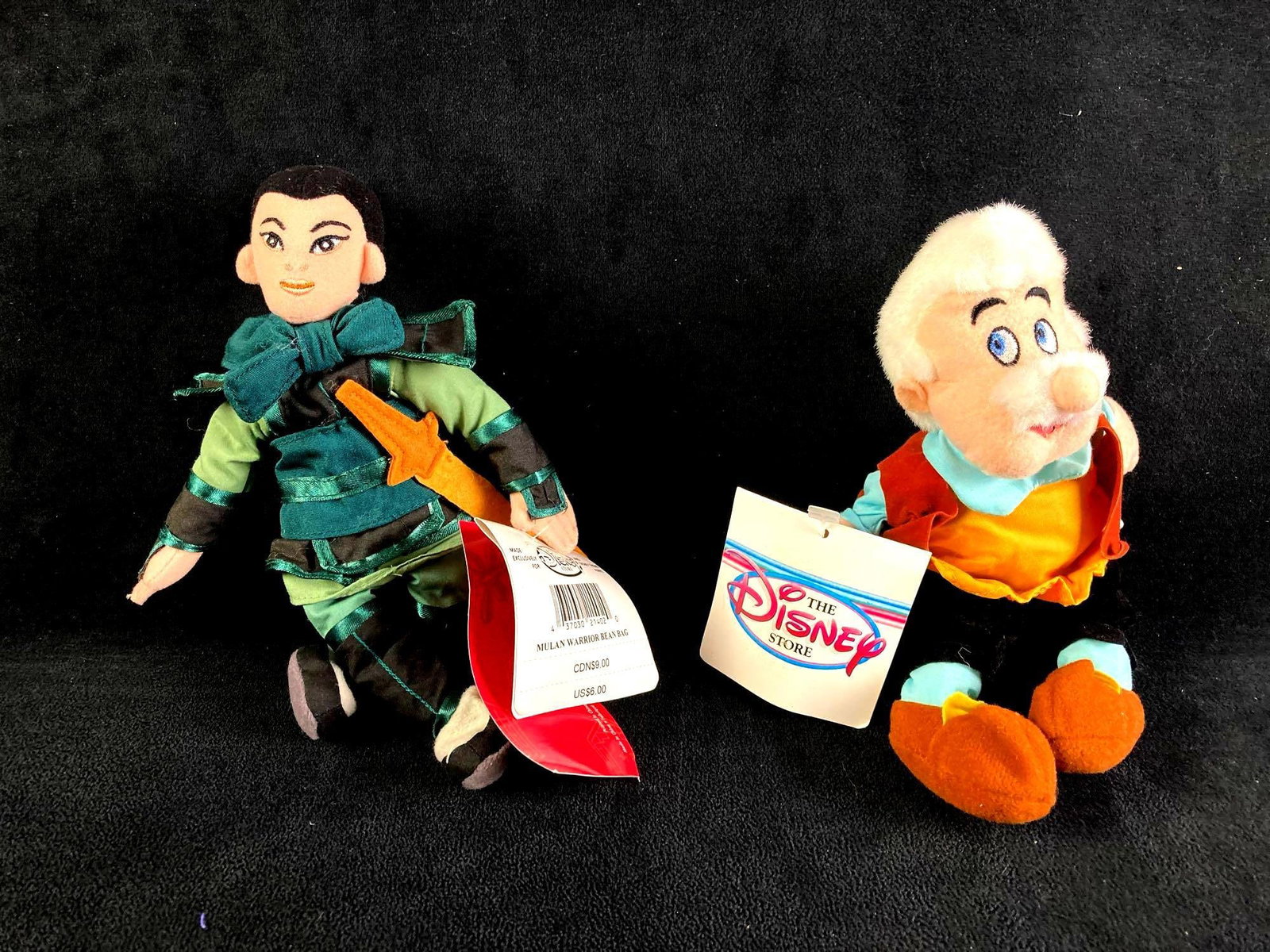 Set of (2) Disney Plush Bean Bag and Gepetto: Up for auction are recent estate finds, two Disney plush bean bag dolls in particular Mulan dressed as a warrior and Gepetto from Pinocchio. Both came from a large collection of Disney items. This