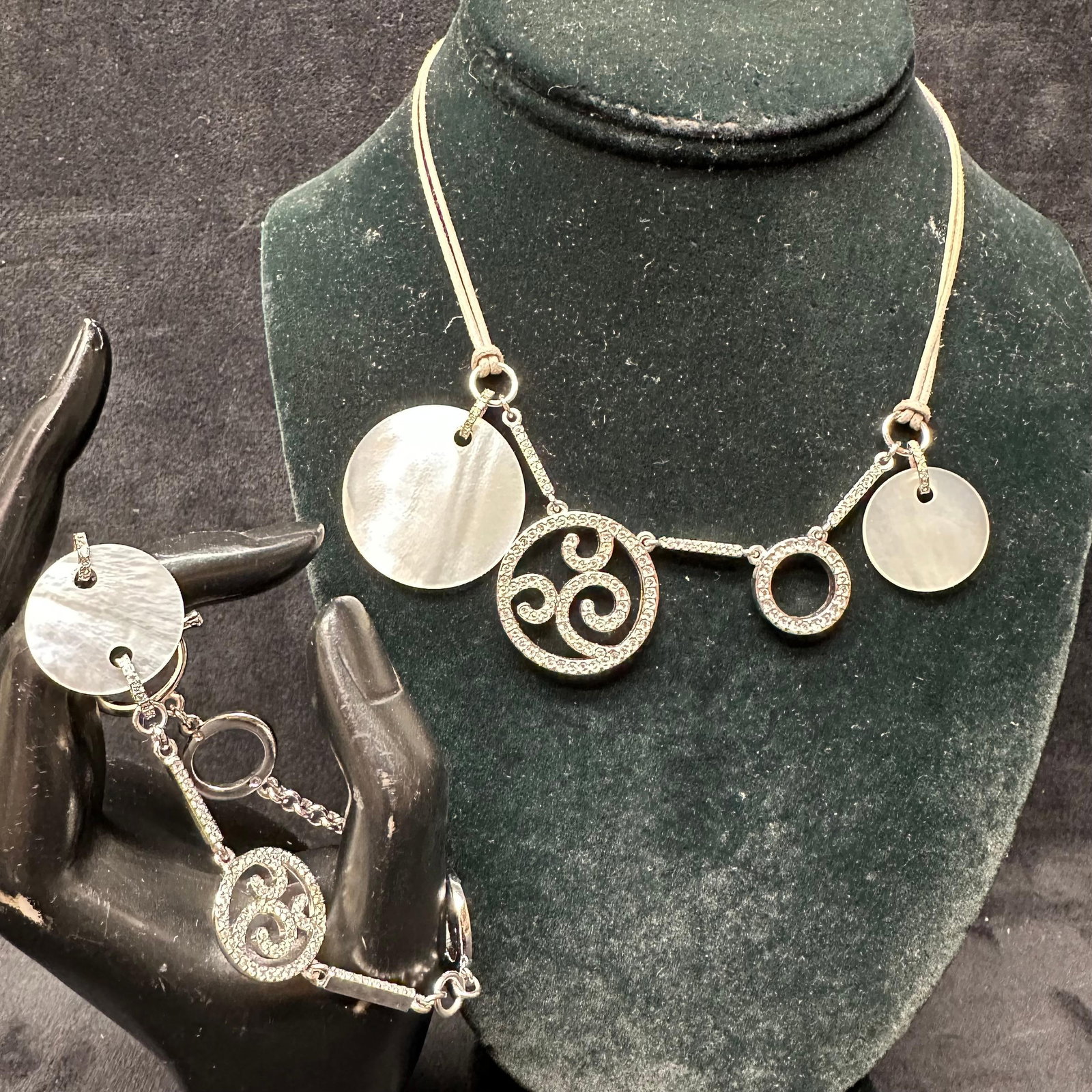 Swarovski Jewelry Swan Circles Round Crystals MOP Discs Bracelet and Necklace Set: Matching necklace and bracelet set featuring round mother-of-pearl discs and pave-set Swarovski crystal accents. Silver-tone metal with suede-style cord necklace and chain bracelet with toggle clasp. 