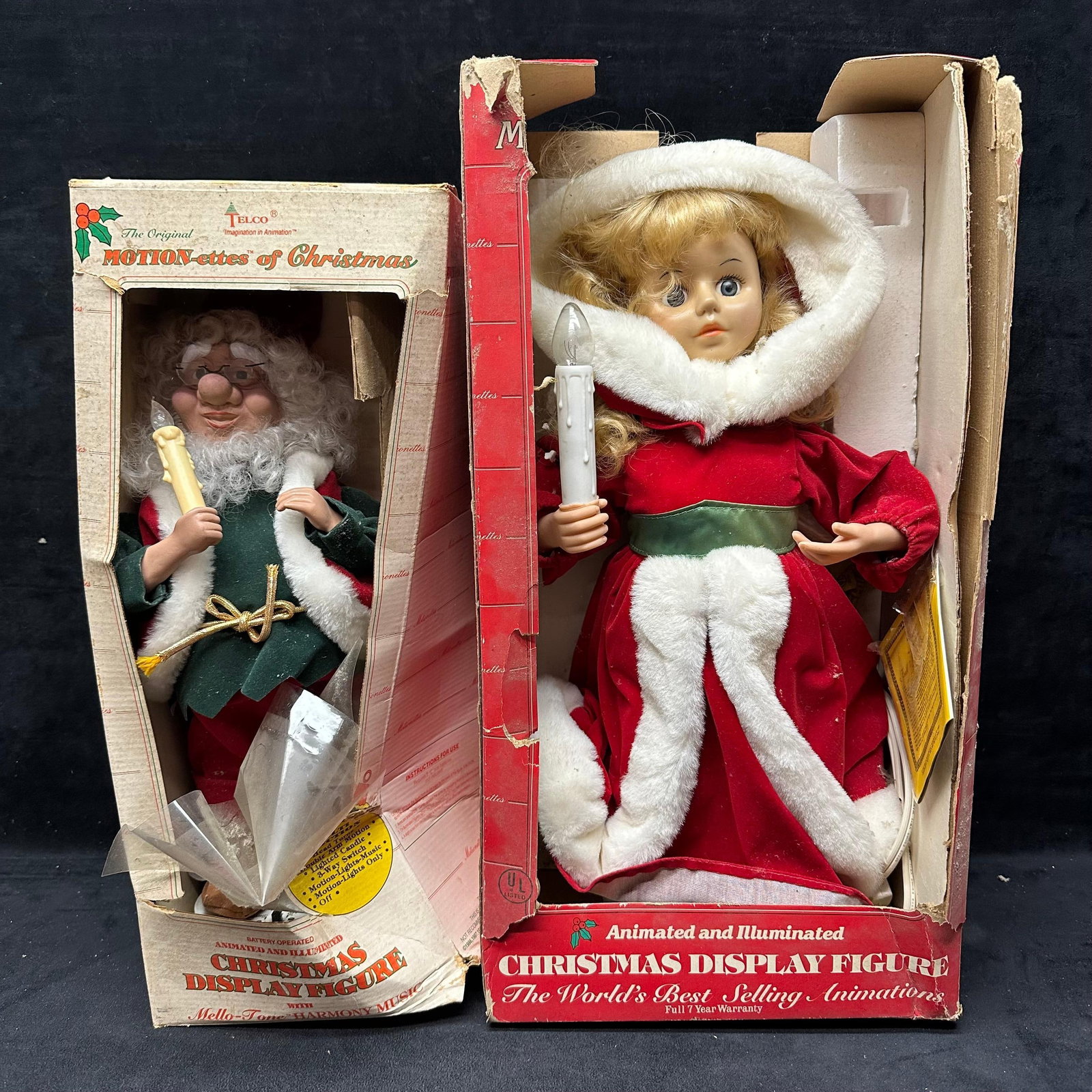 Pair of Telco Motion-ettes of Christmas Animated Display Figures in Original Boxes: The lot includes two vintage Telco Motion-ettes of Christmas animated and illuminated display figures, each in its original box. Figures include a Santa-style elf holding a candle and a girl in r