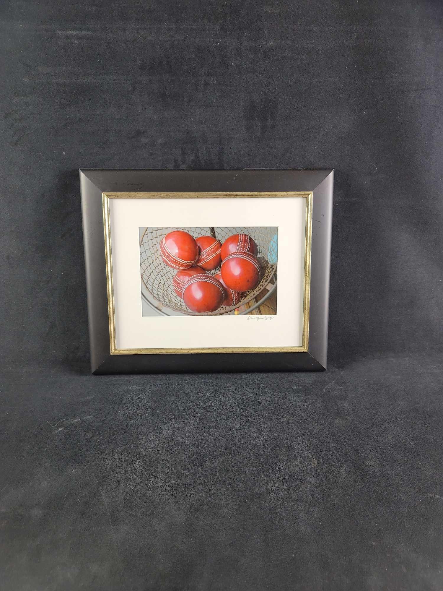 Photograph by Etta Jean Juge Cricket Leather Ball Red: Photograph is of red leather cricket balls. Photo was taken by artist Etta Jean Juge. It is framed, matted, and signed. In good condition. Approx. measures 17 1/2" x 14 1/2", weight is 2.5 lbs