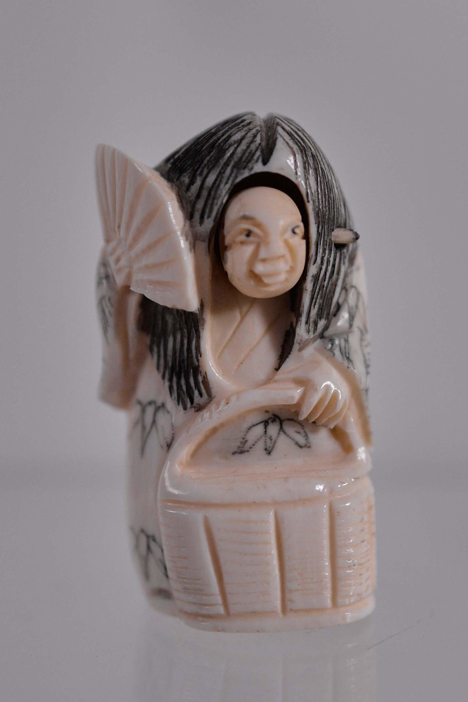 Netsuke man with a fan - Début XXème siècle: Netsuke man with a fan (Début XXème siècle) Description: Bone netsuke, man with a fan with a changing face, signature below Dimension (PO): 2" x 1 1/4" x 3/4" Dimension (CM): 5.08 x 3.17 x 1.90 cm