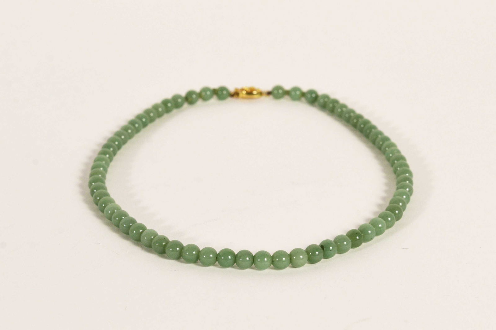 Jadeite bead necklace: Jadeite bead necklace Description: Necklace of round jadeite beads, 8 mm each, 14 karat yellow gold closure, 20 inches in length. Condition report: Upon request, We will gladly answer all your inquiri
